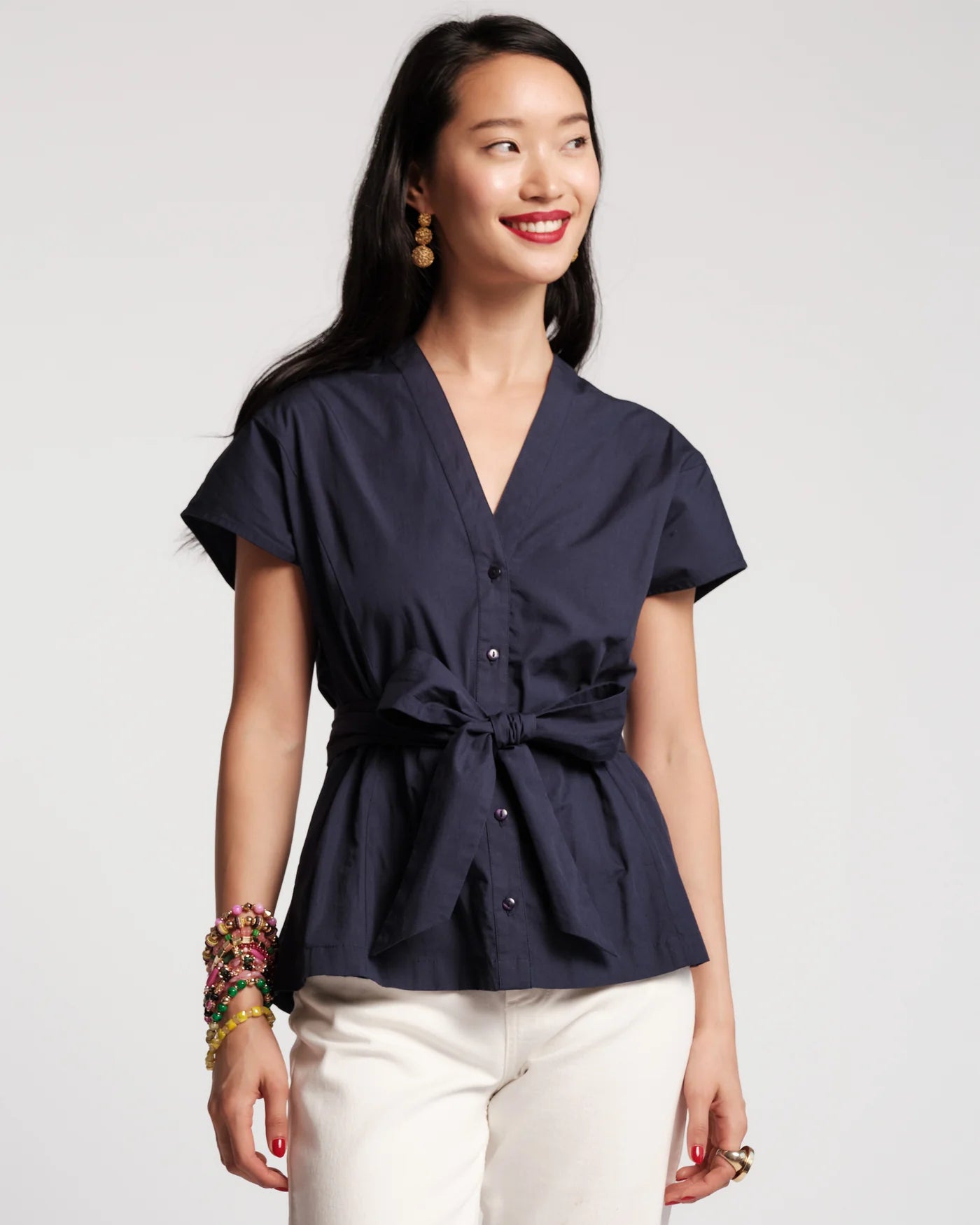 Woman wearing a navy blue top with a tie waist on a white background