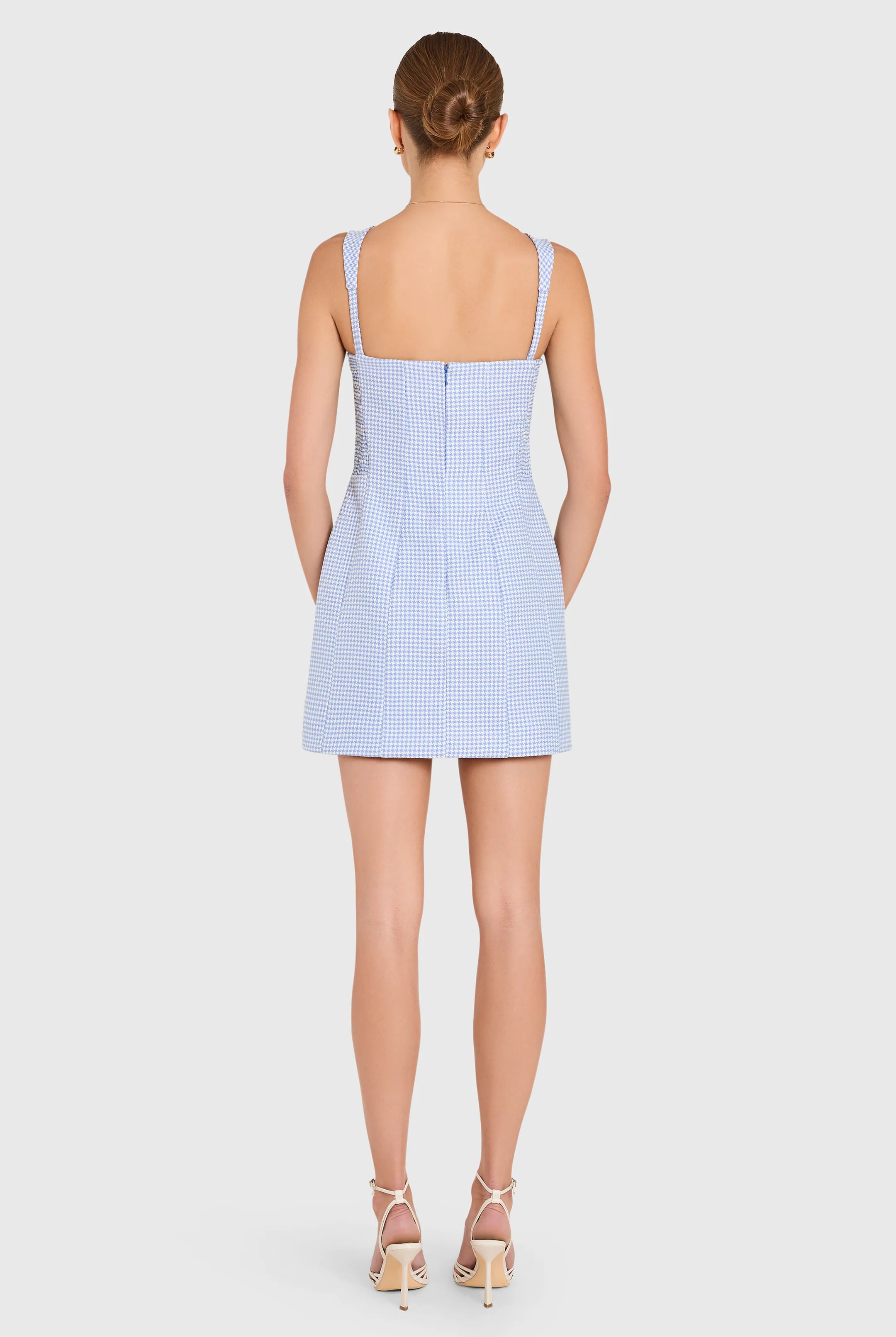 Woman wearing a light blue checkered dress on a white background