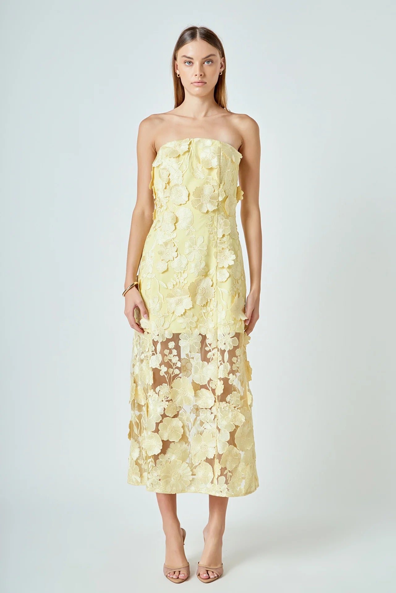 Woman wearing a strapless yellow floral dress on a white background