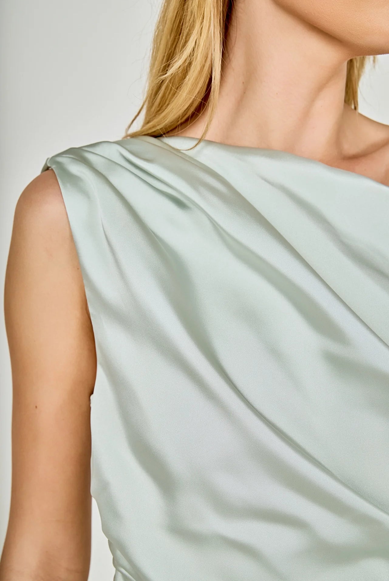 Light green satin dress with a draped neckline on a neutral background