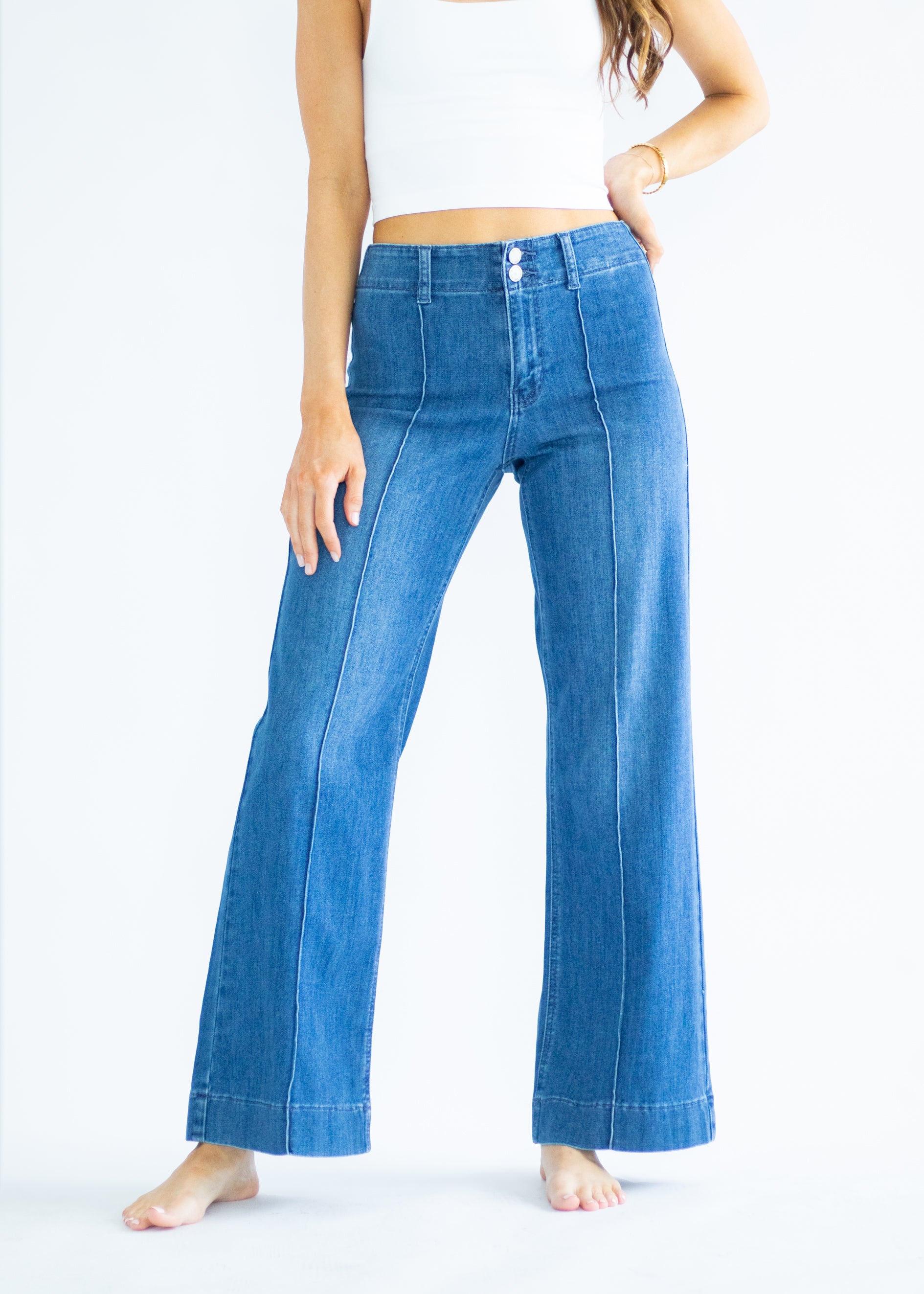 Person wearing blue flared jeans on a white background
