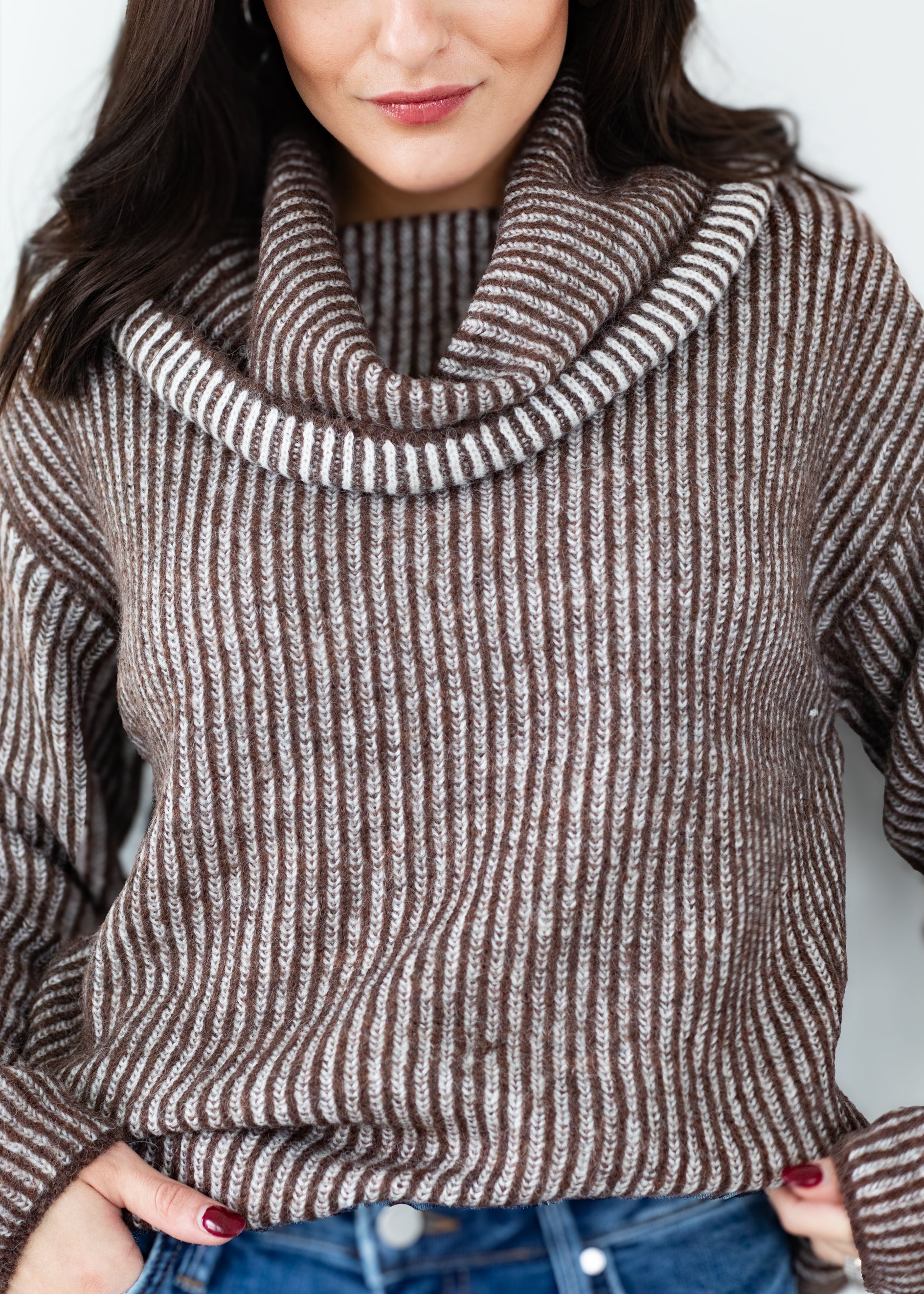 Woman wearing a brown and white striped sweater with a cowl neck.