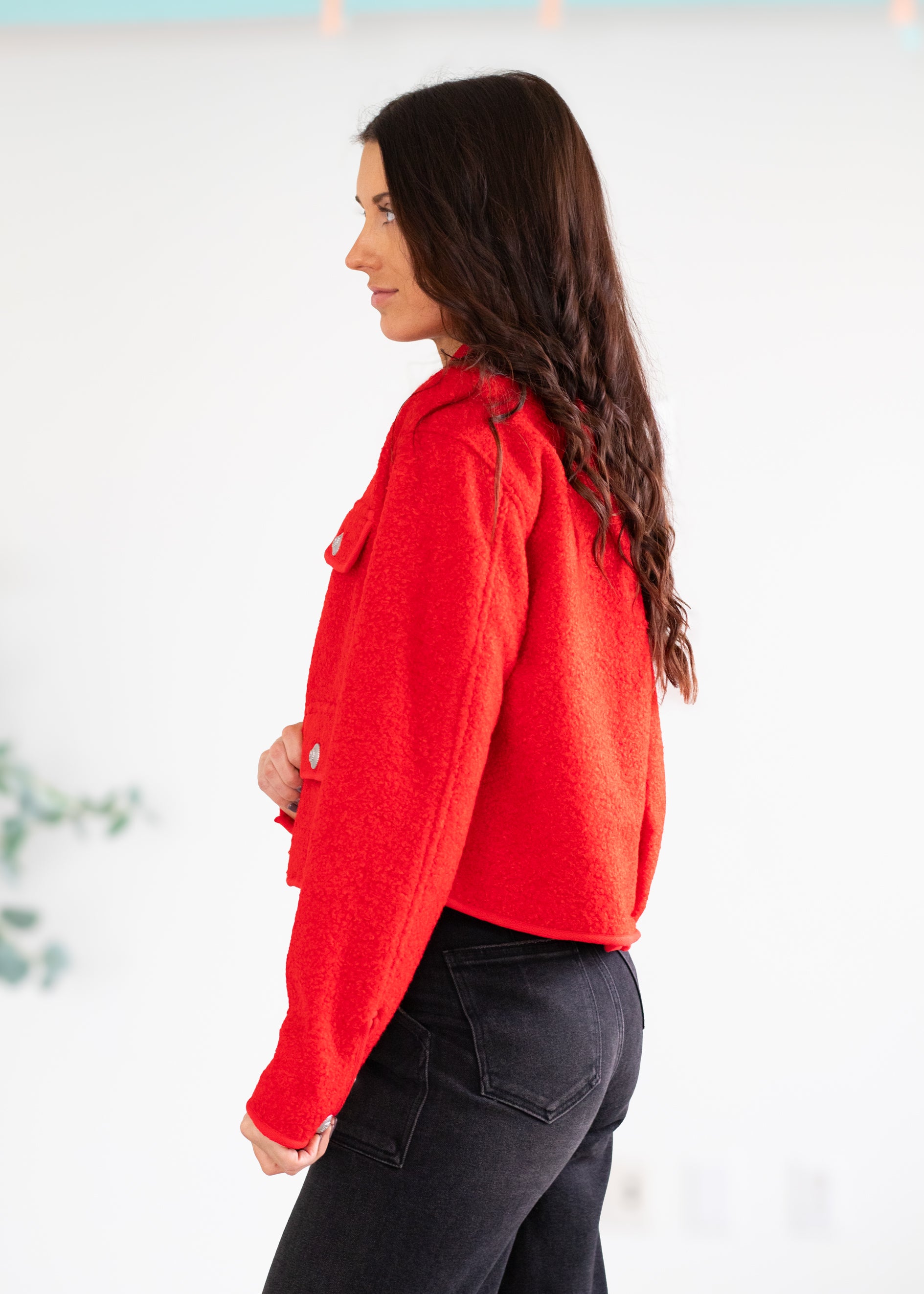 Woman wearing a red jacket and black pants against a white background