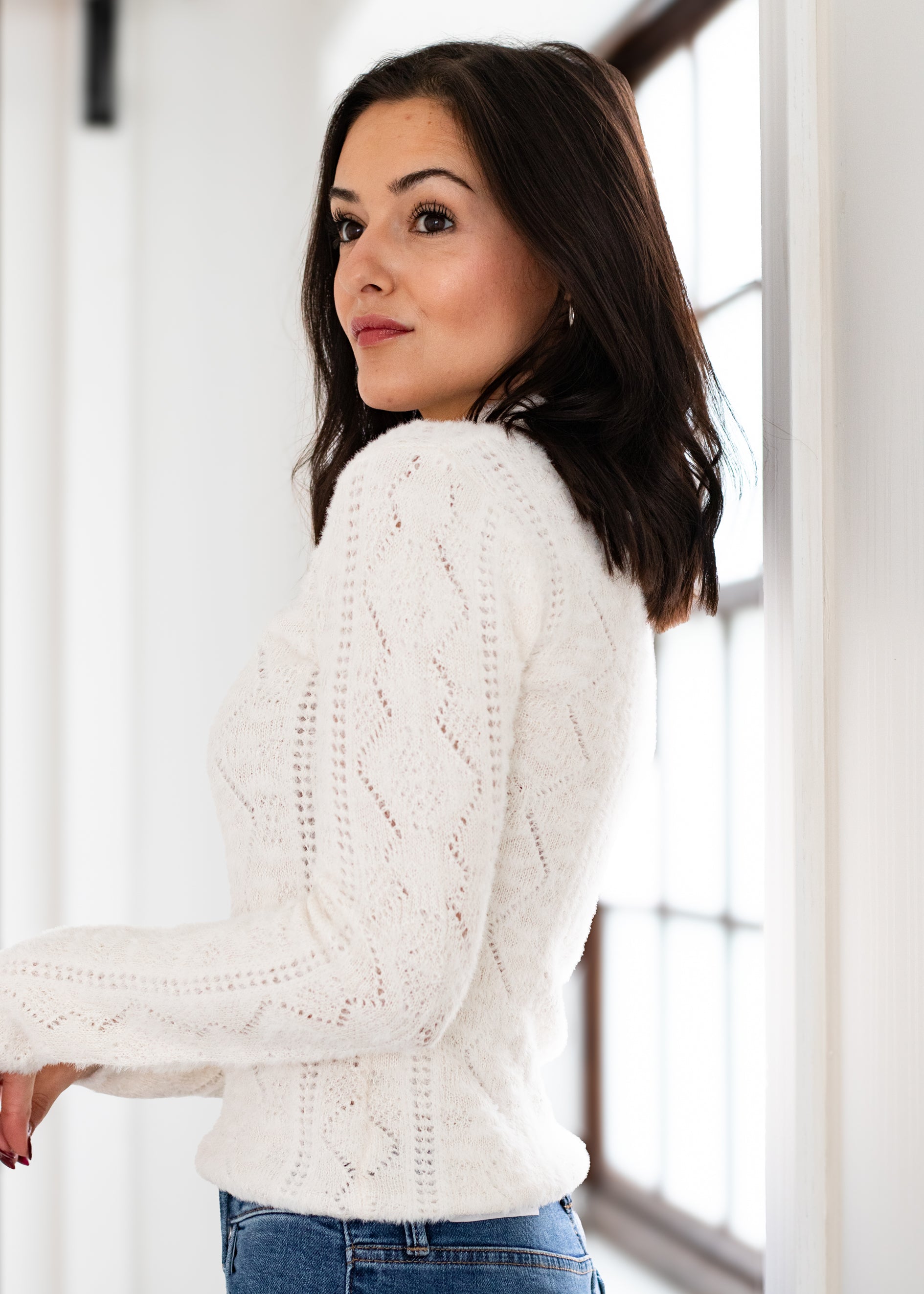 Woman wearing a white cable knit sweater indoors