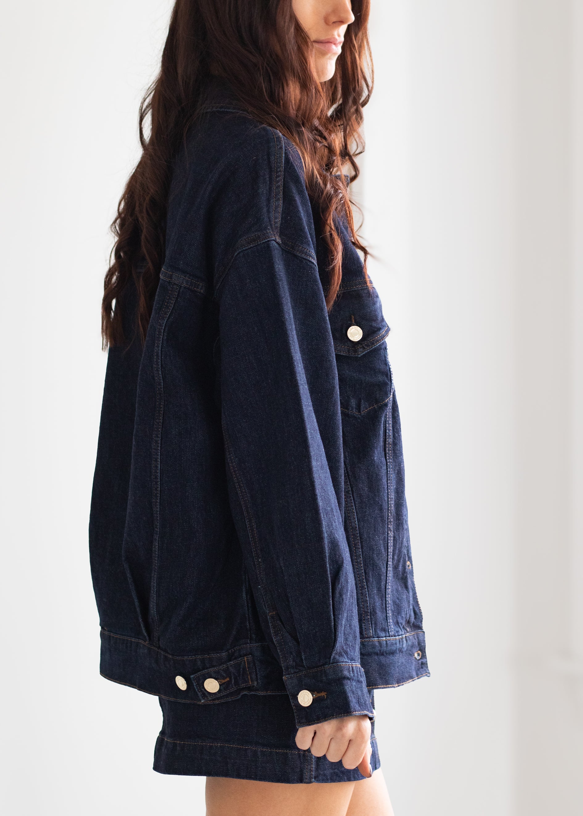 Person wearing a blue denim jacket against a white background