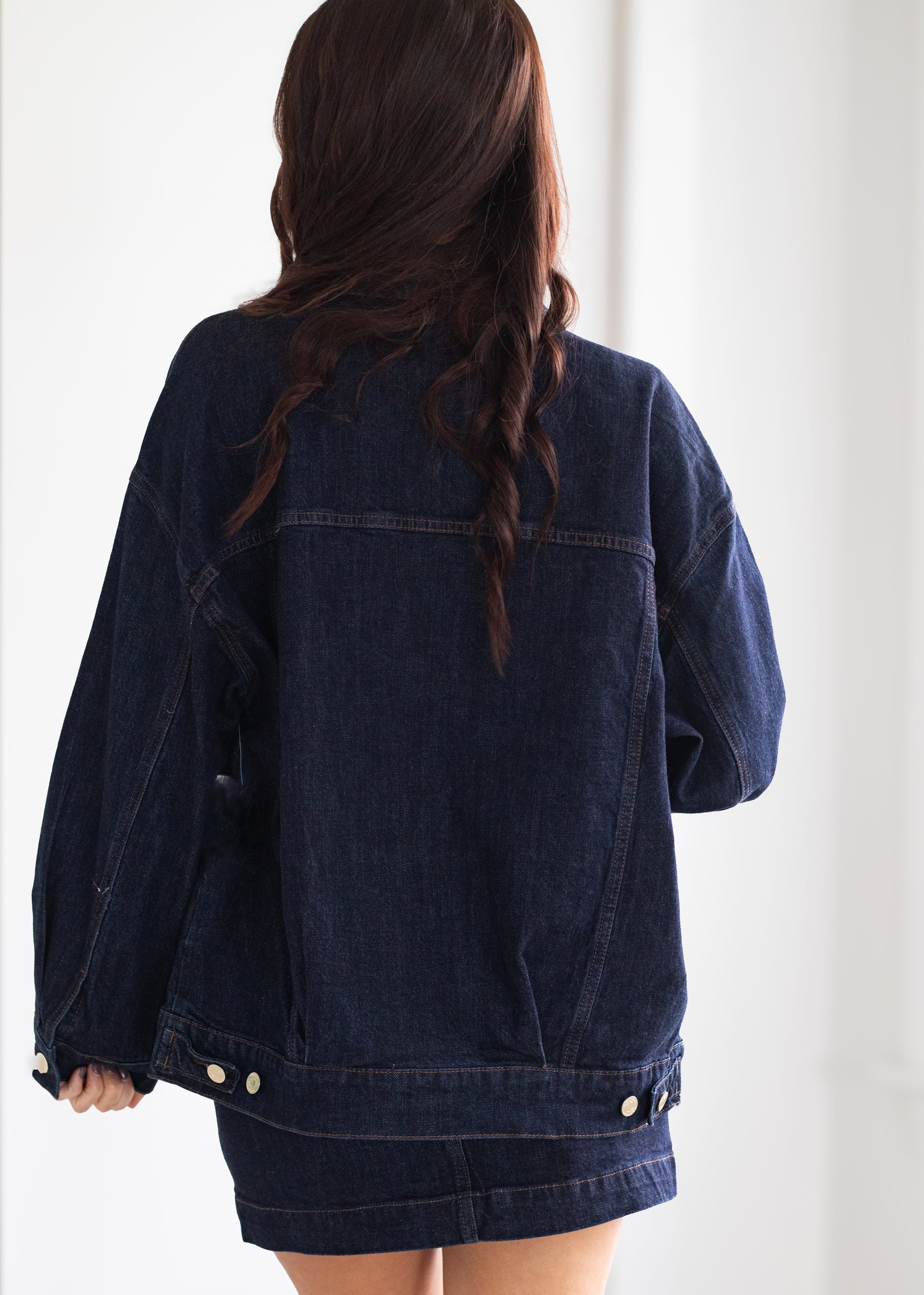 Person wearing a dark denim jacket on a white background