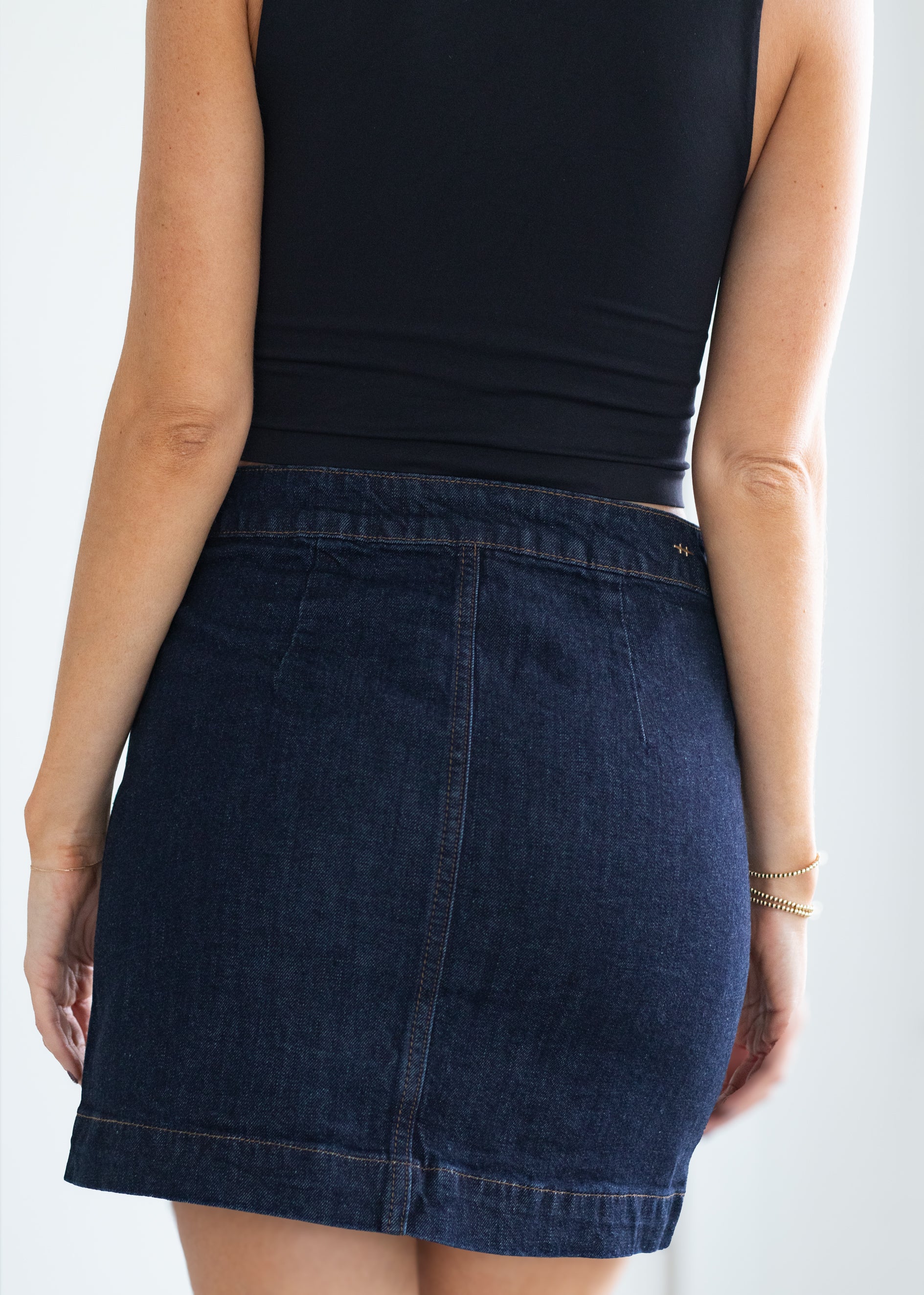 Person wearing a dark blue denim skirt on a white background