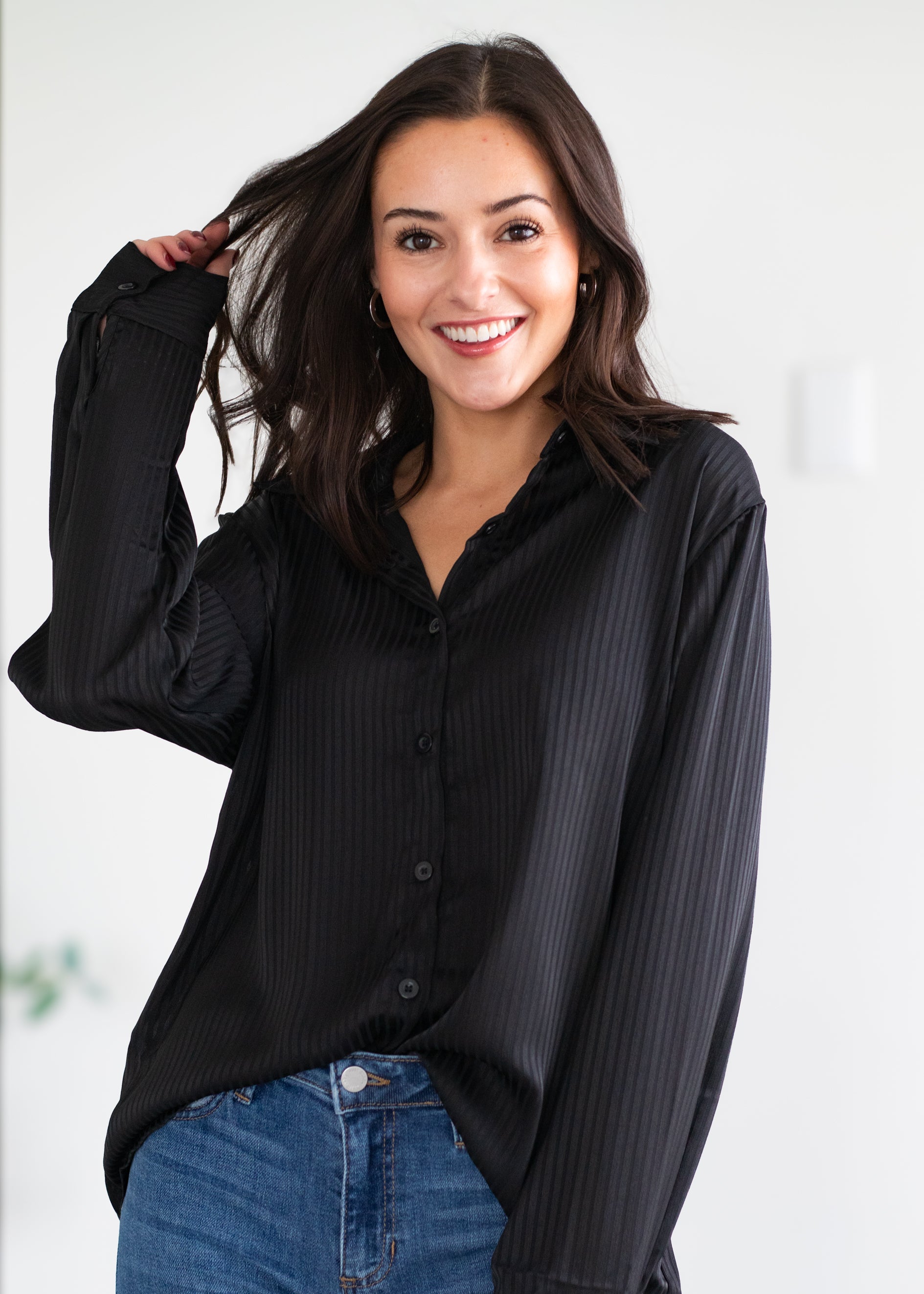 Woman wearing a black blouse and blue jeans against a white background