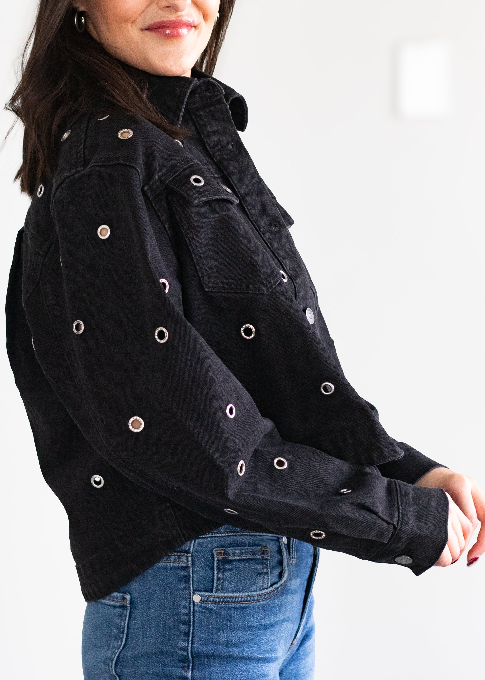 Person wearing a black jacket with button details on a white background