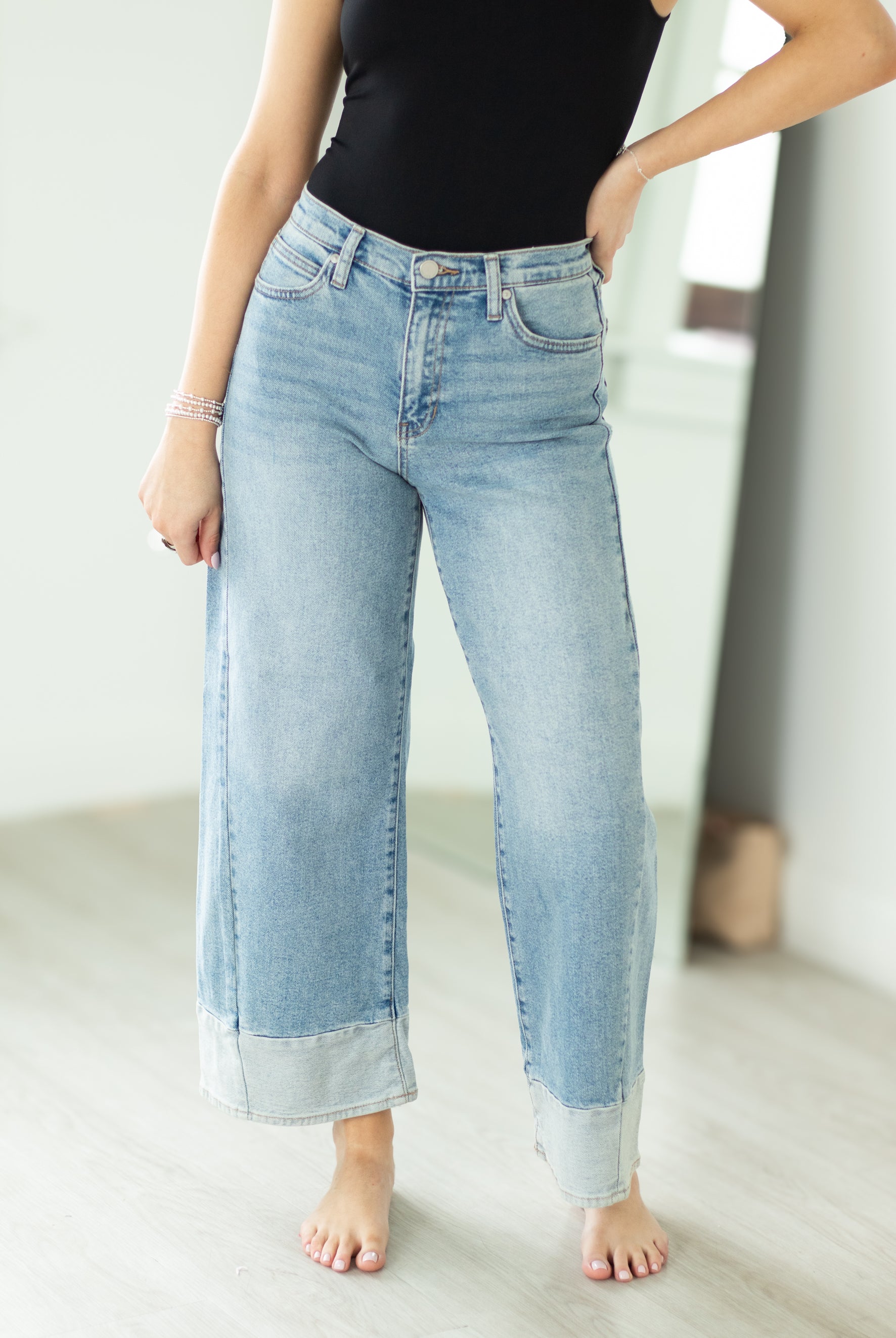 Person wearing light blue jeans and a black top in a minimalistic setting