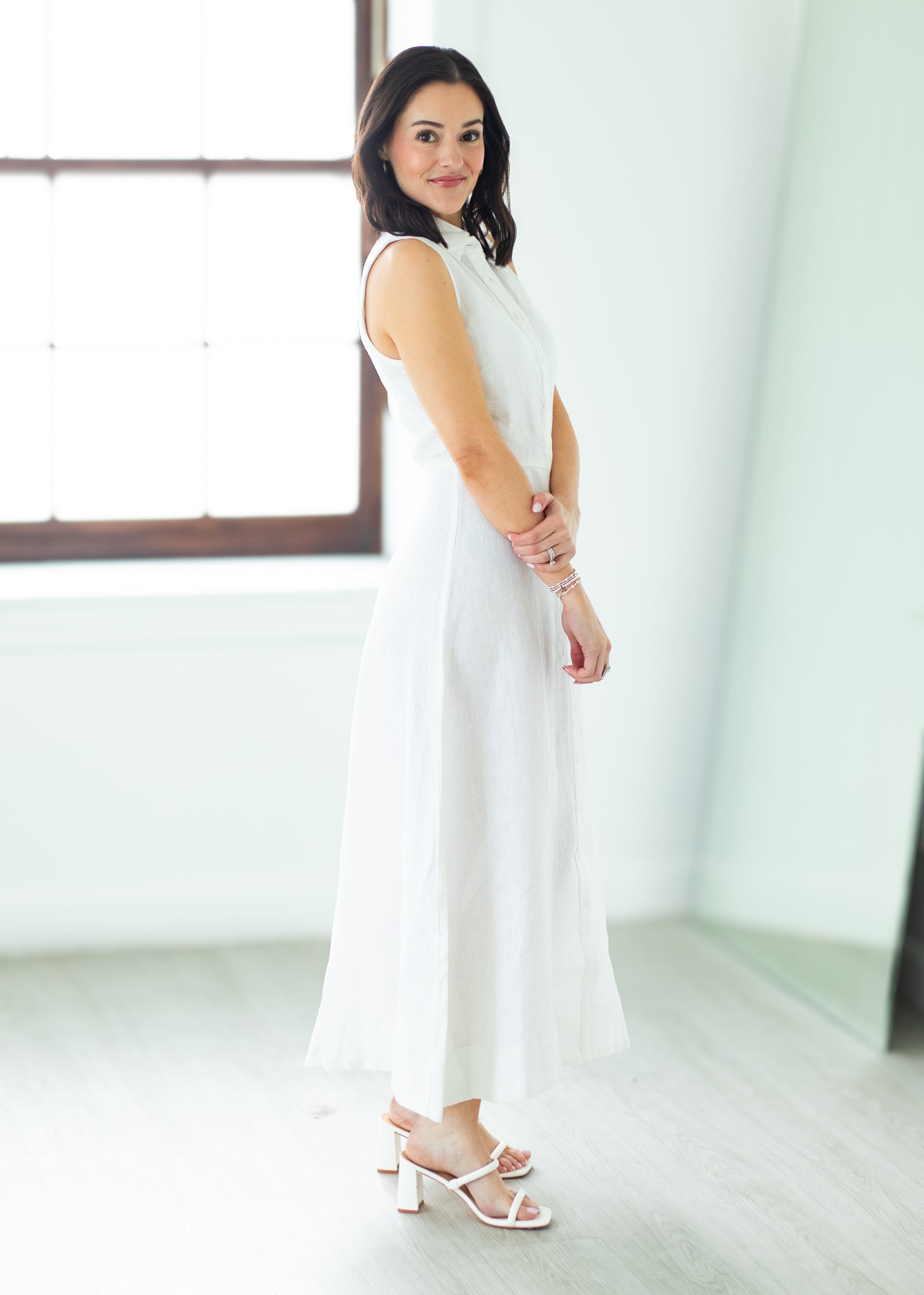 Woman wearing a long white dress against a beige background