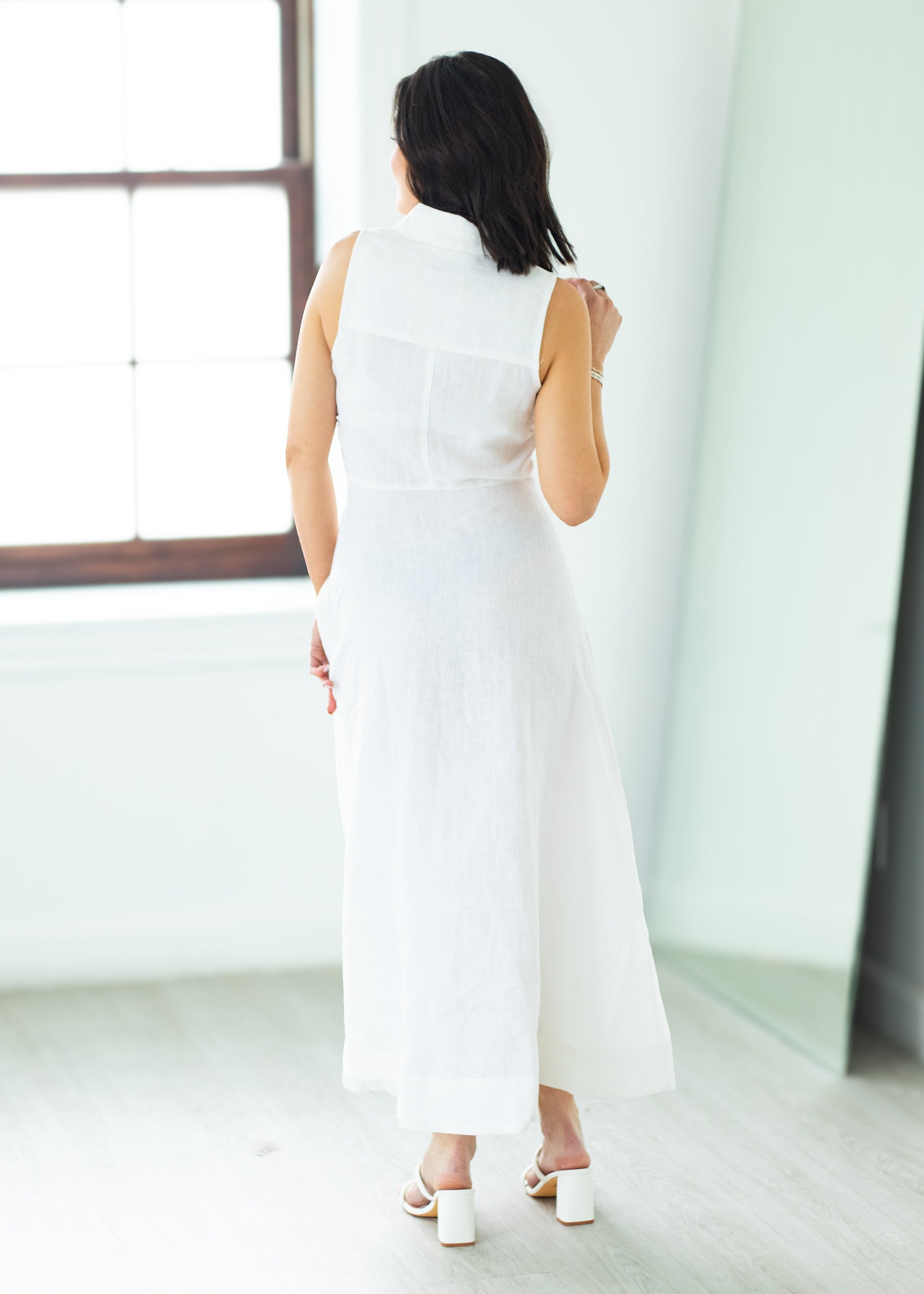 Woman wearing a long white dress against a beige background