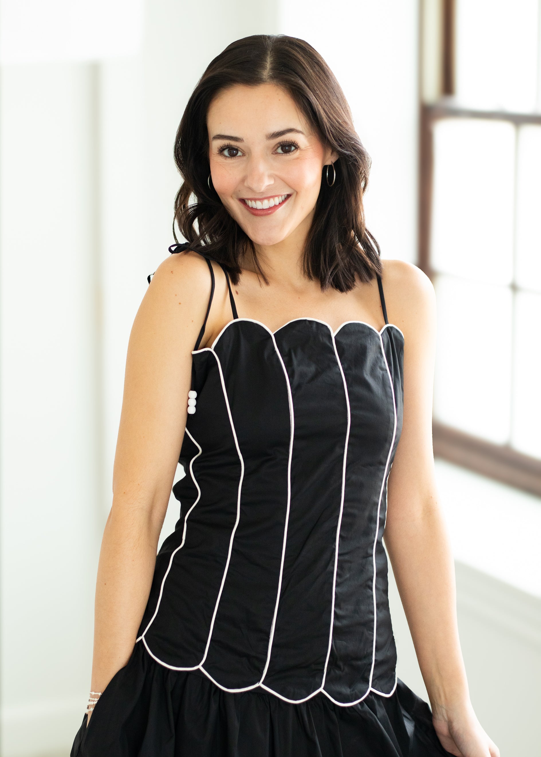 Woman wearing a black set with white trim on a beige background