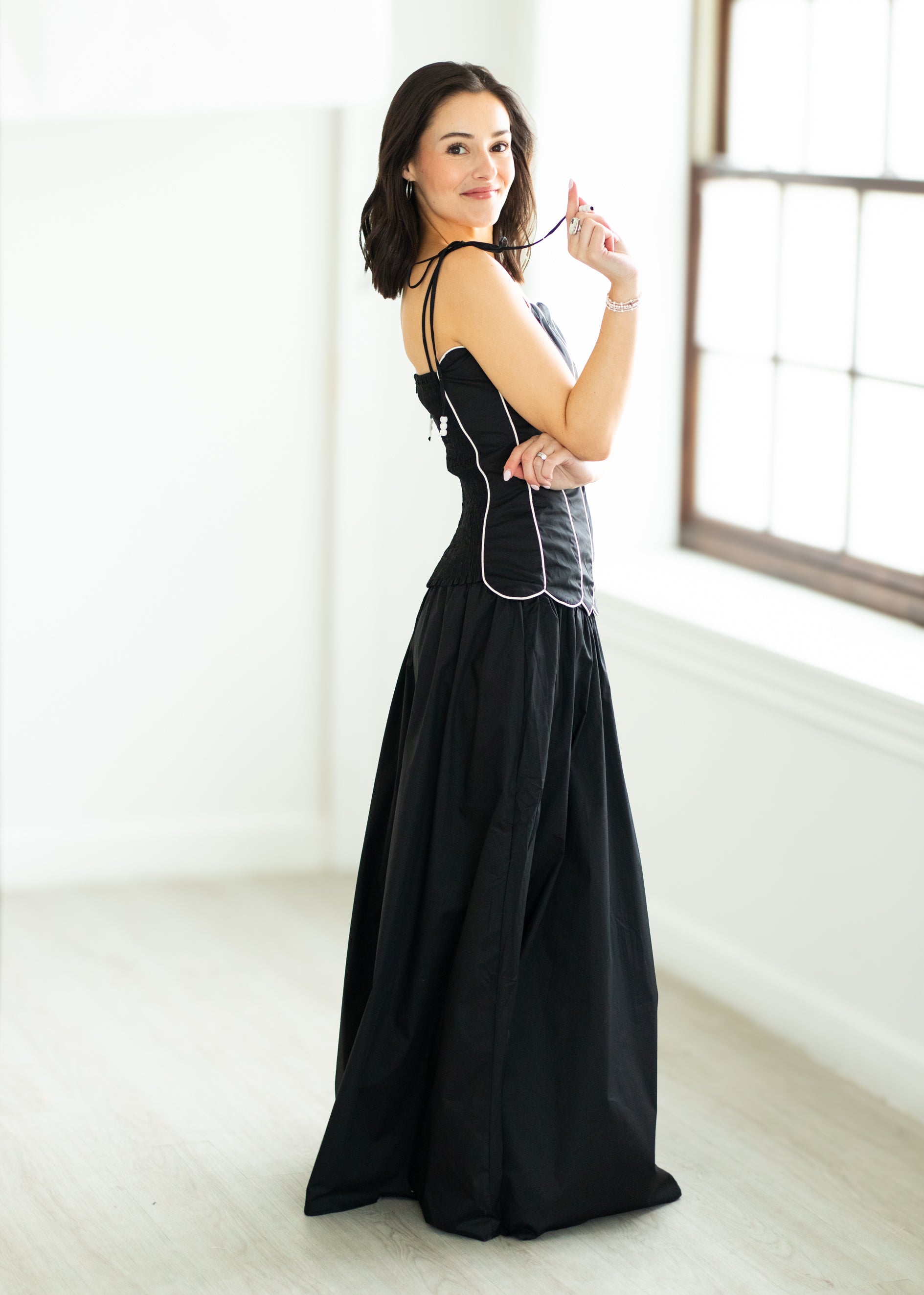 Woman wearing a black set with white trim on a beige background