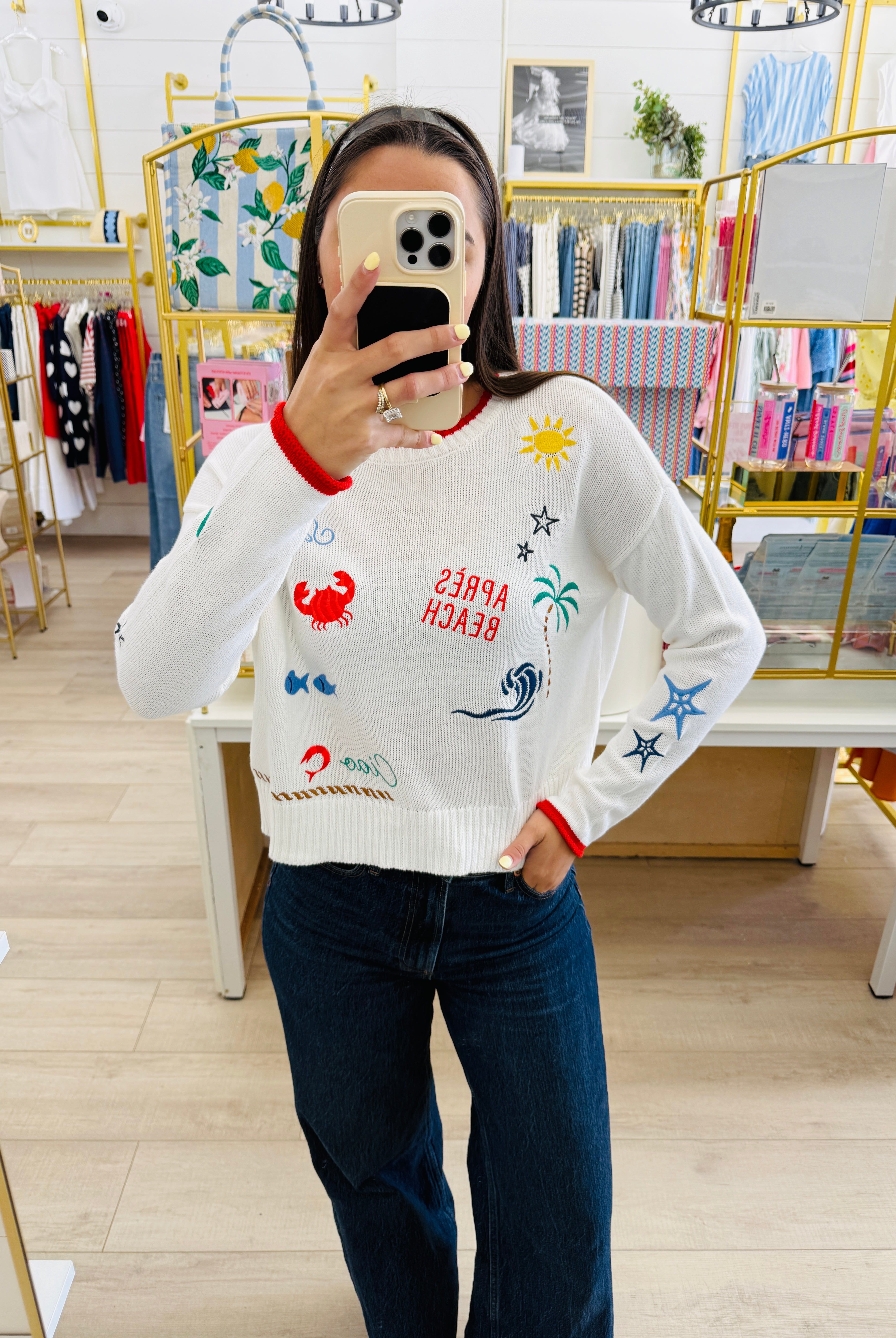 Person wearing a white sweater with colorful designs in a store setting