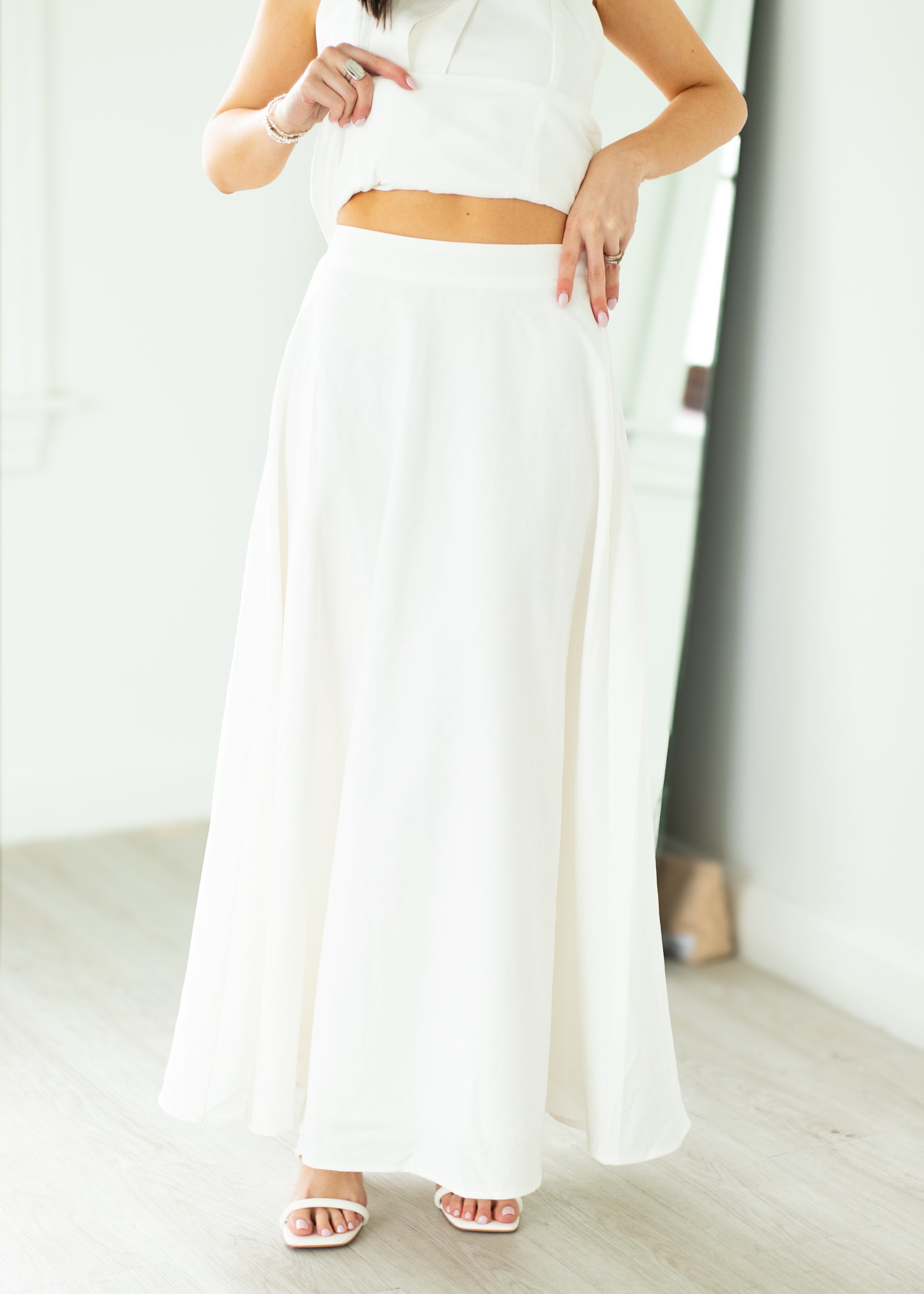 Woman wearing a white halter neck dress with a belt on a beige background