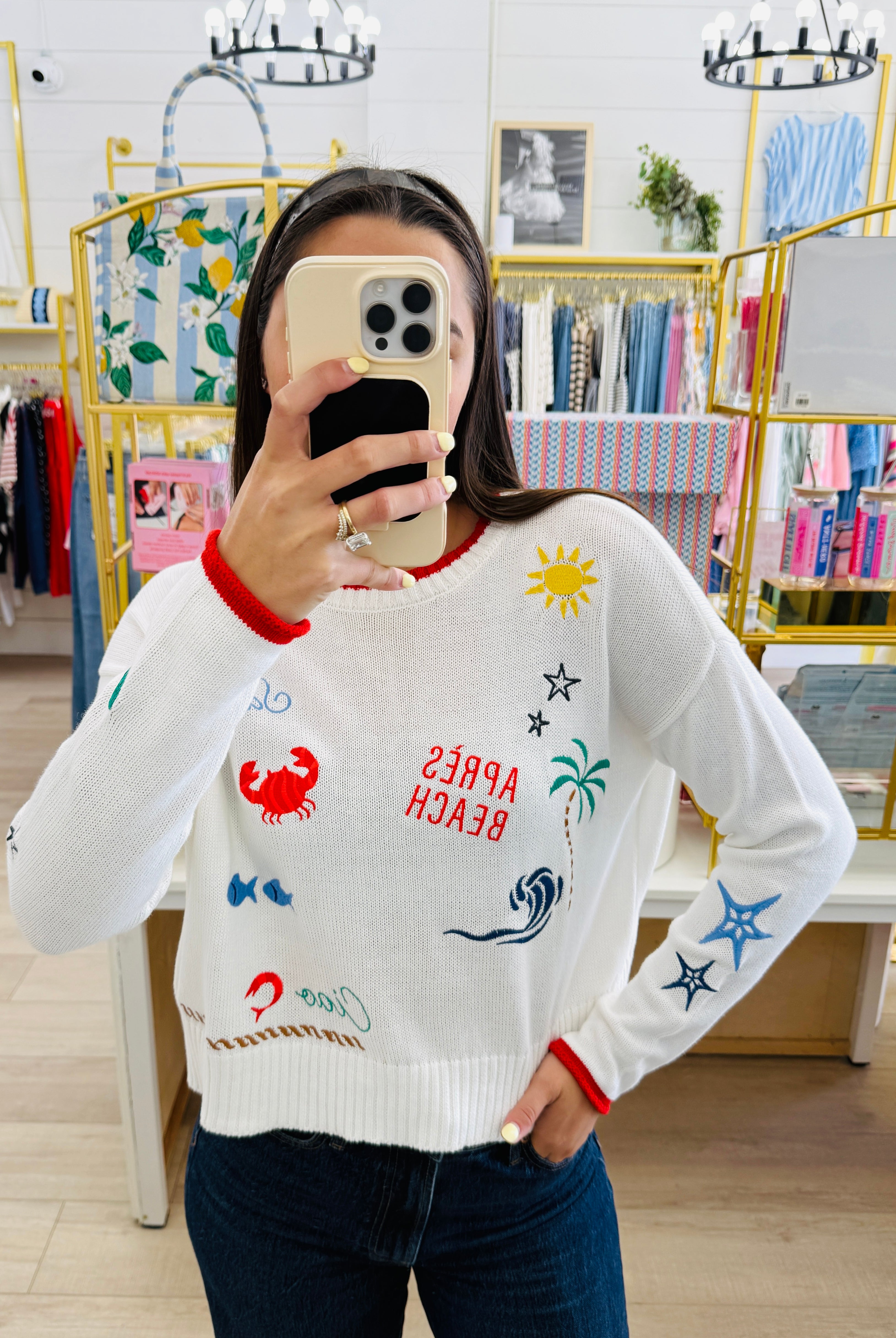 Person wearing a white sweater with colorful graphics in a store setting