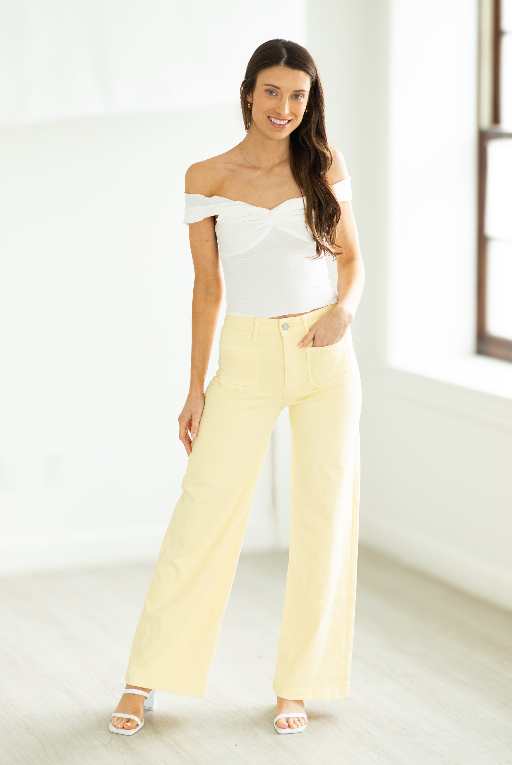 Woman wearing a polka dot top and yellow pants on a white background