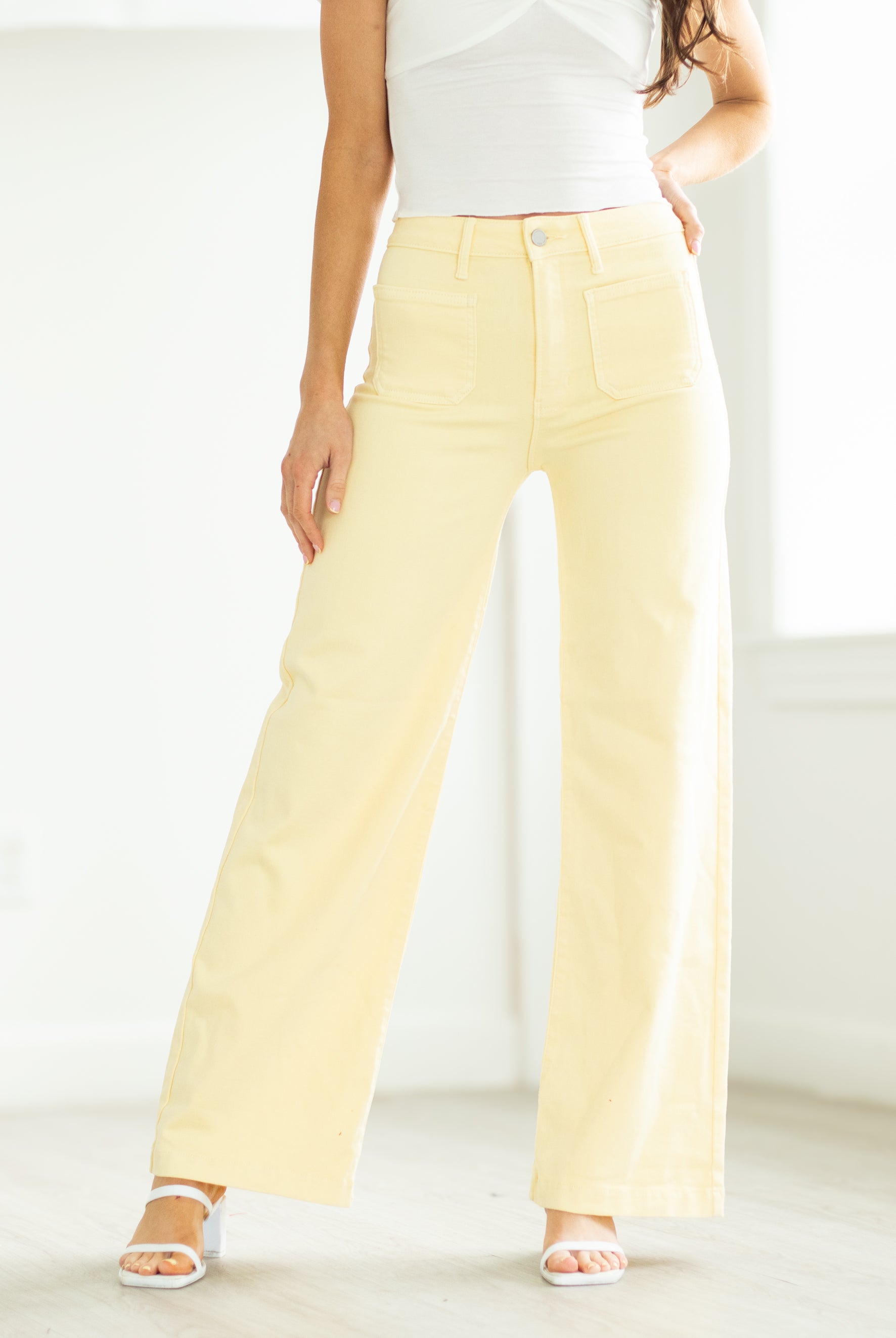 Woman wearing a polka dot top and yellow pants on a white background