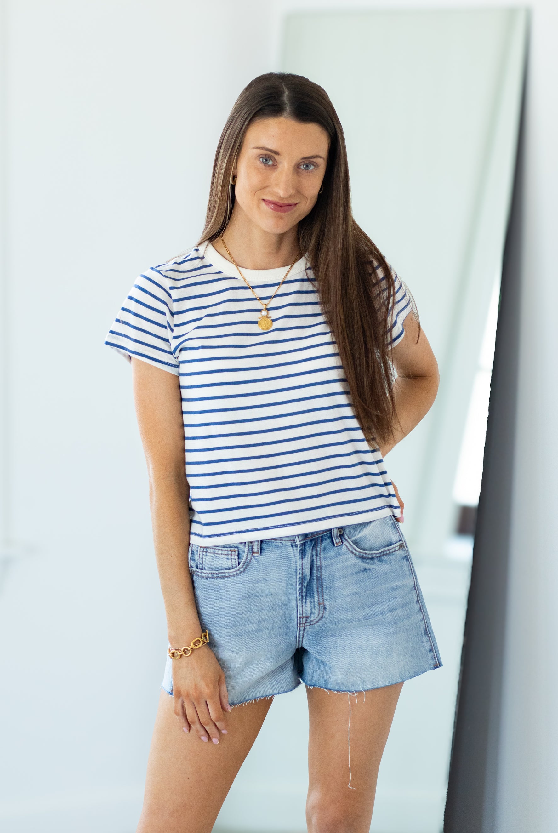 Woman wearing a striped shirt and denim shorts in an indoor setting
