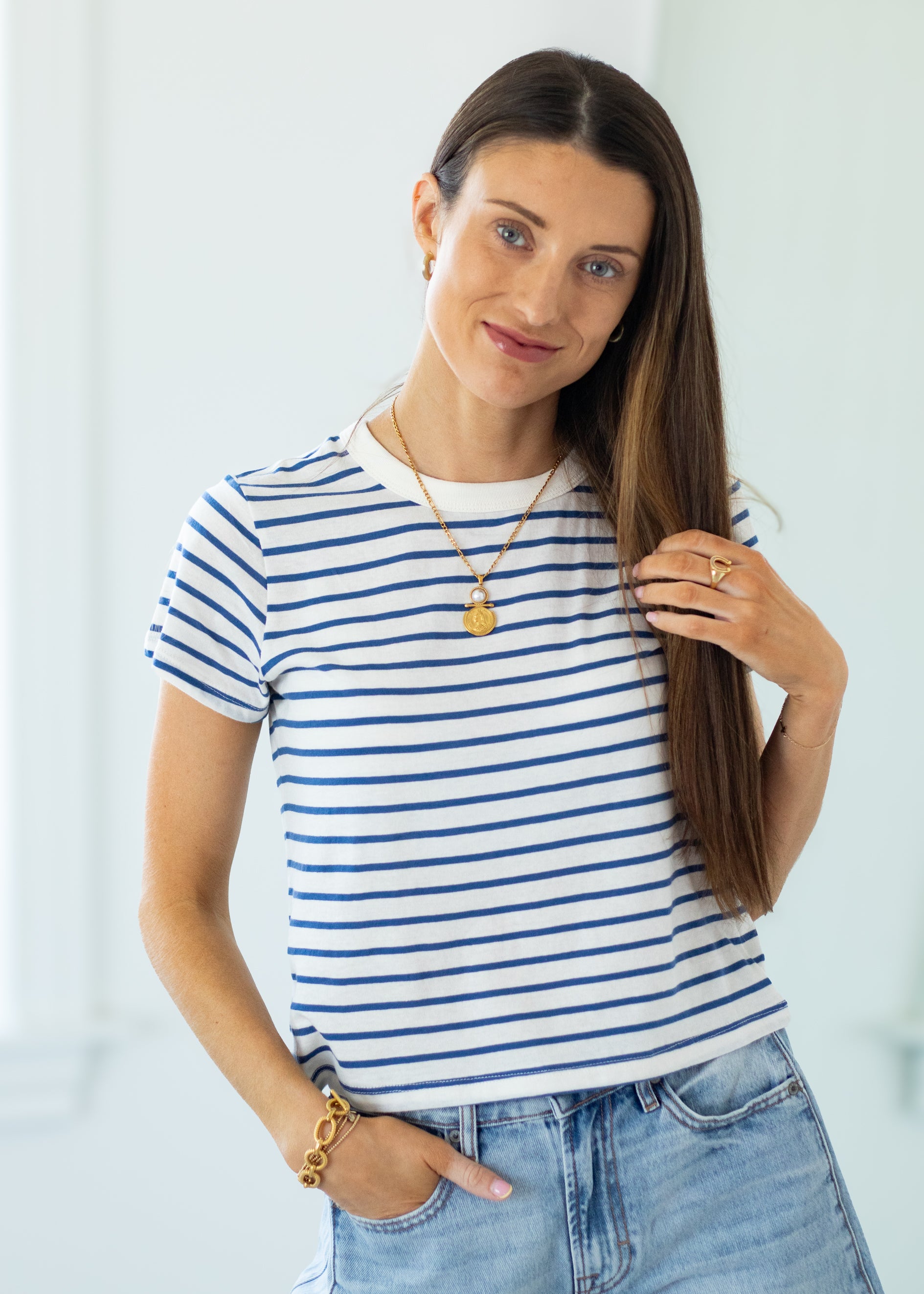 Woman wearing a striped shirt and jeans with a plain background