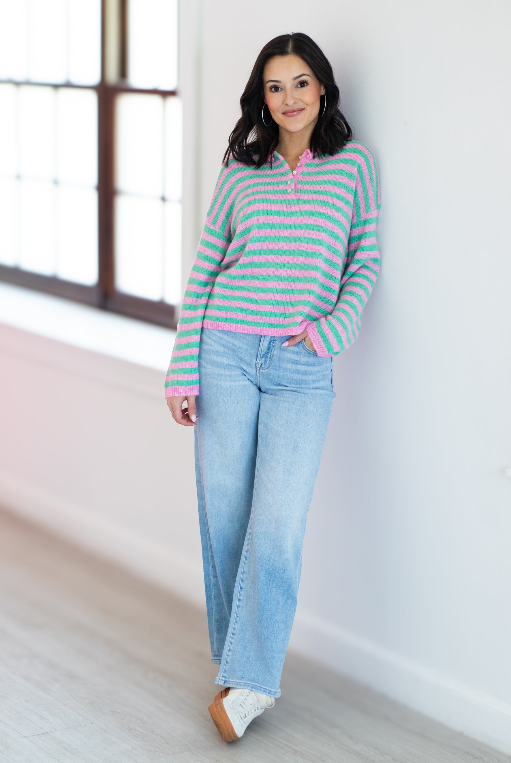 Woman wearing a striped sweater and jeans indoors.