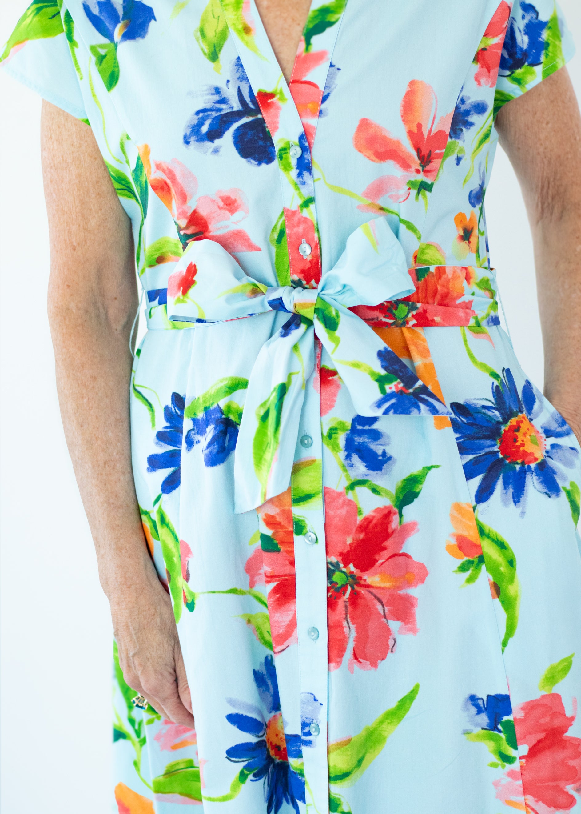 Colorful floral dress with a tie waist on a light blue background