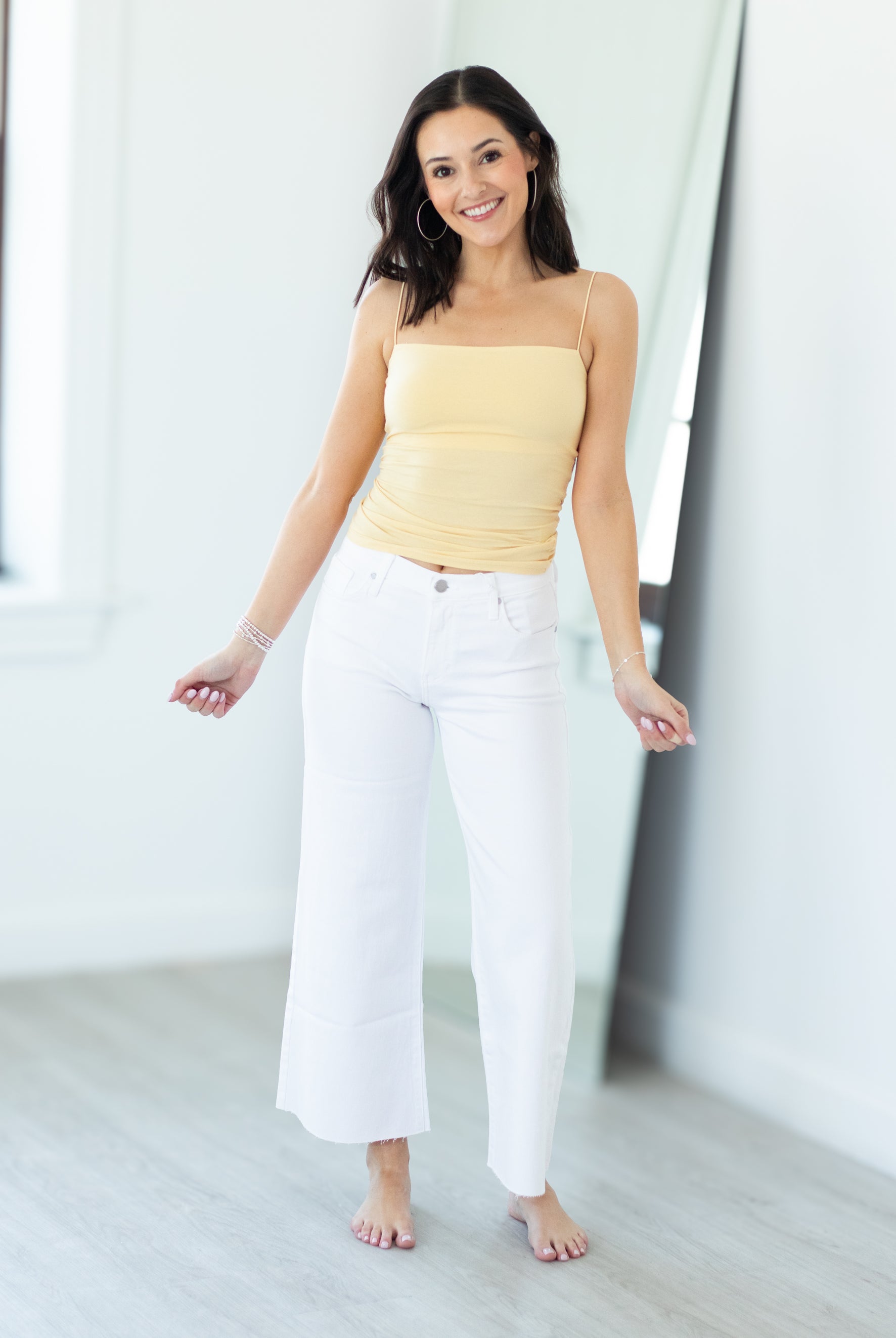 Woman wearing a yellow top and white pants in a bright room