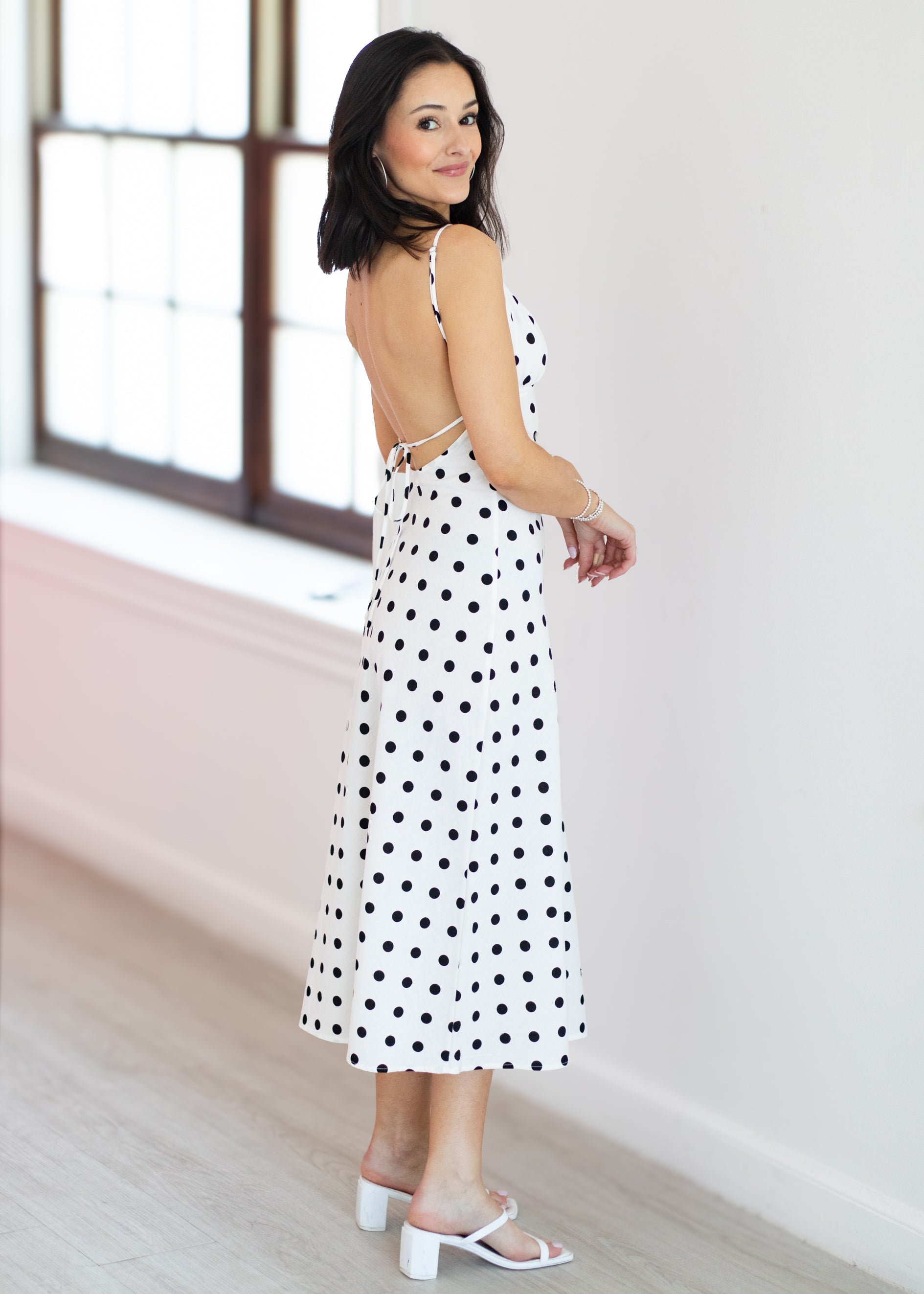 Woman wearing a polka dot dress in a minimal indoor setting