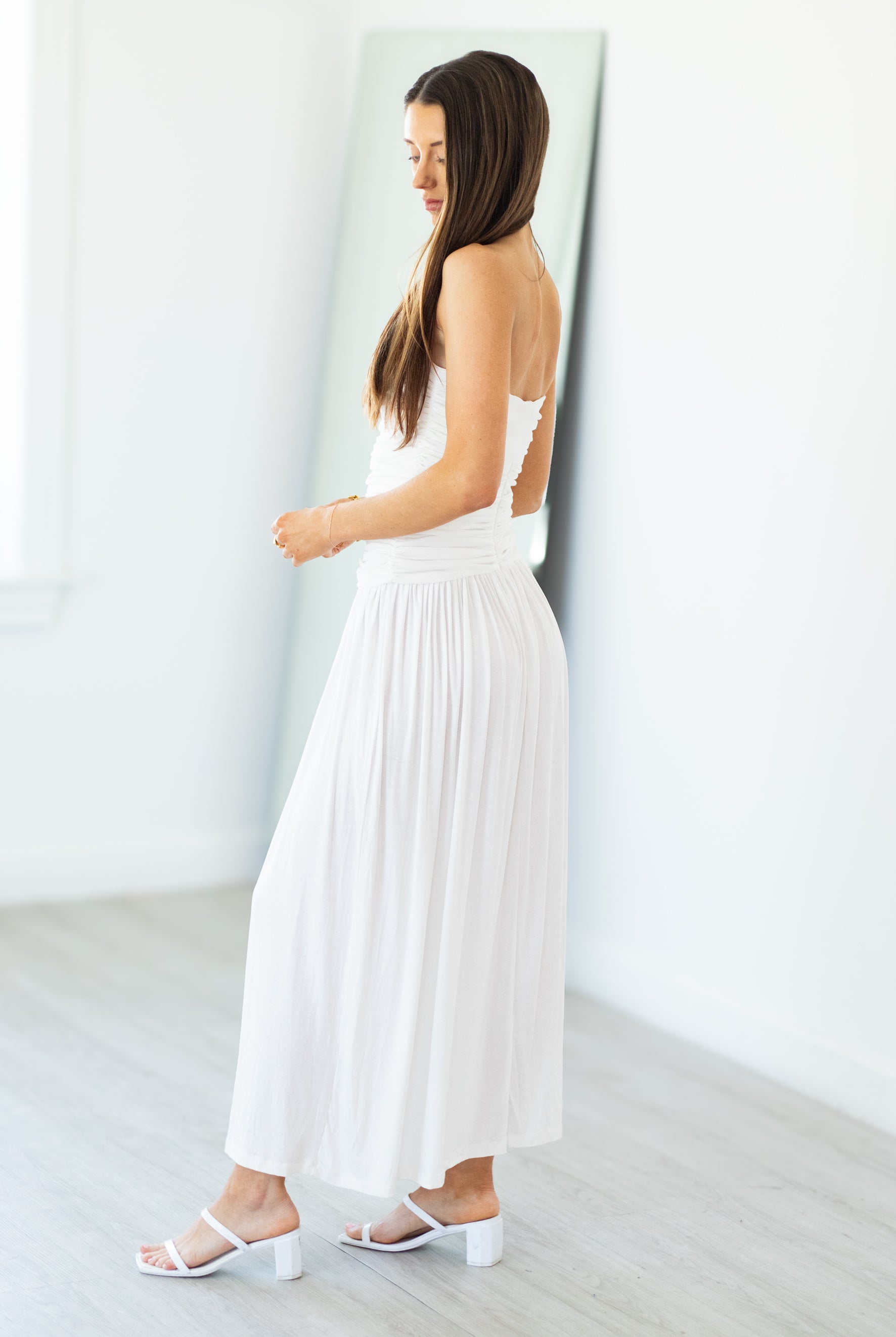 Woman wearing a white dress with cut-out shoulders in a minimalistic setting