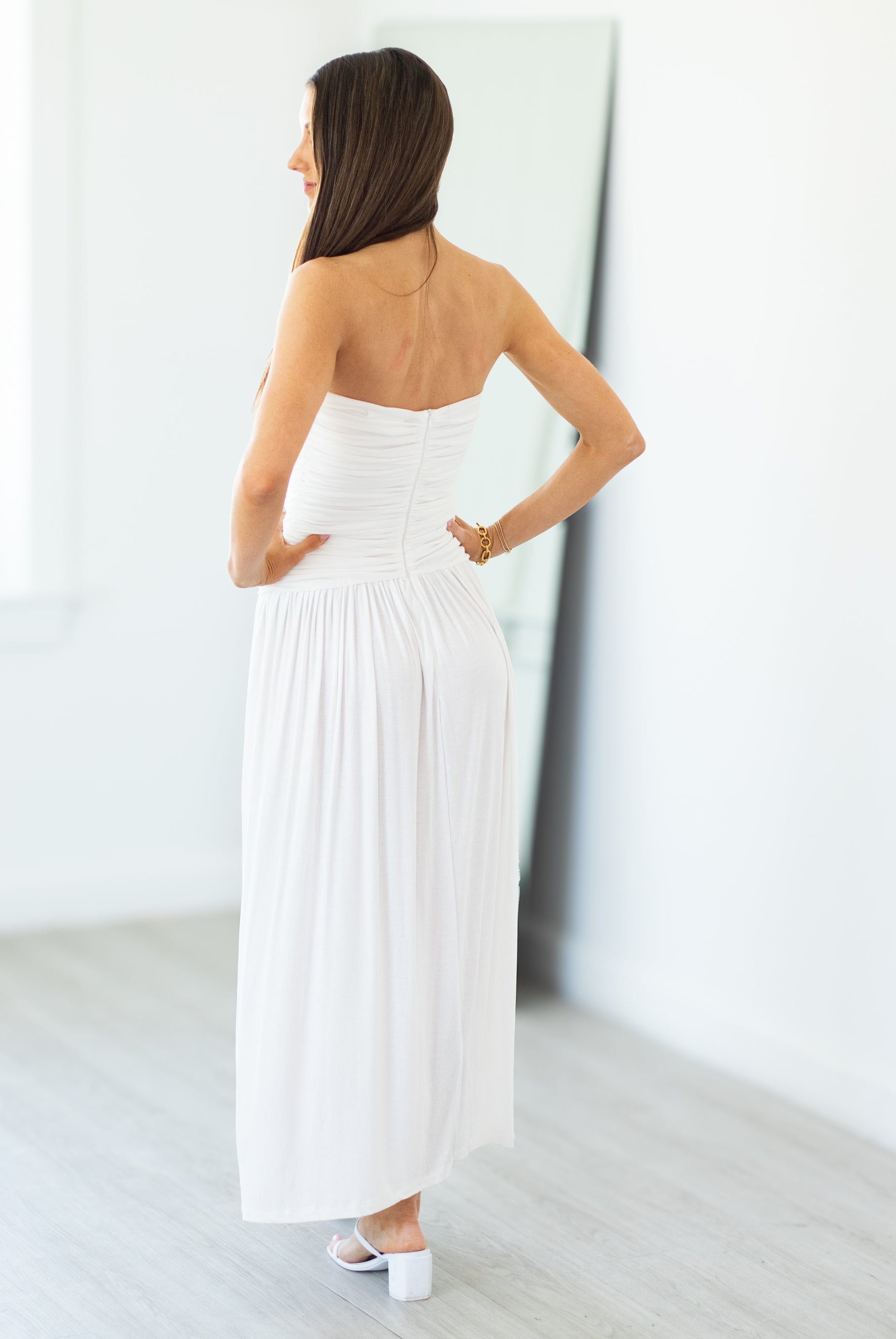 Woman wearing a white strapless dress in a minimalistic setting