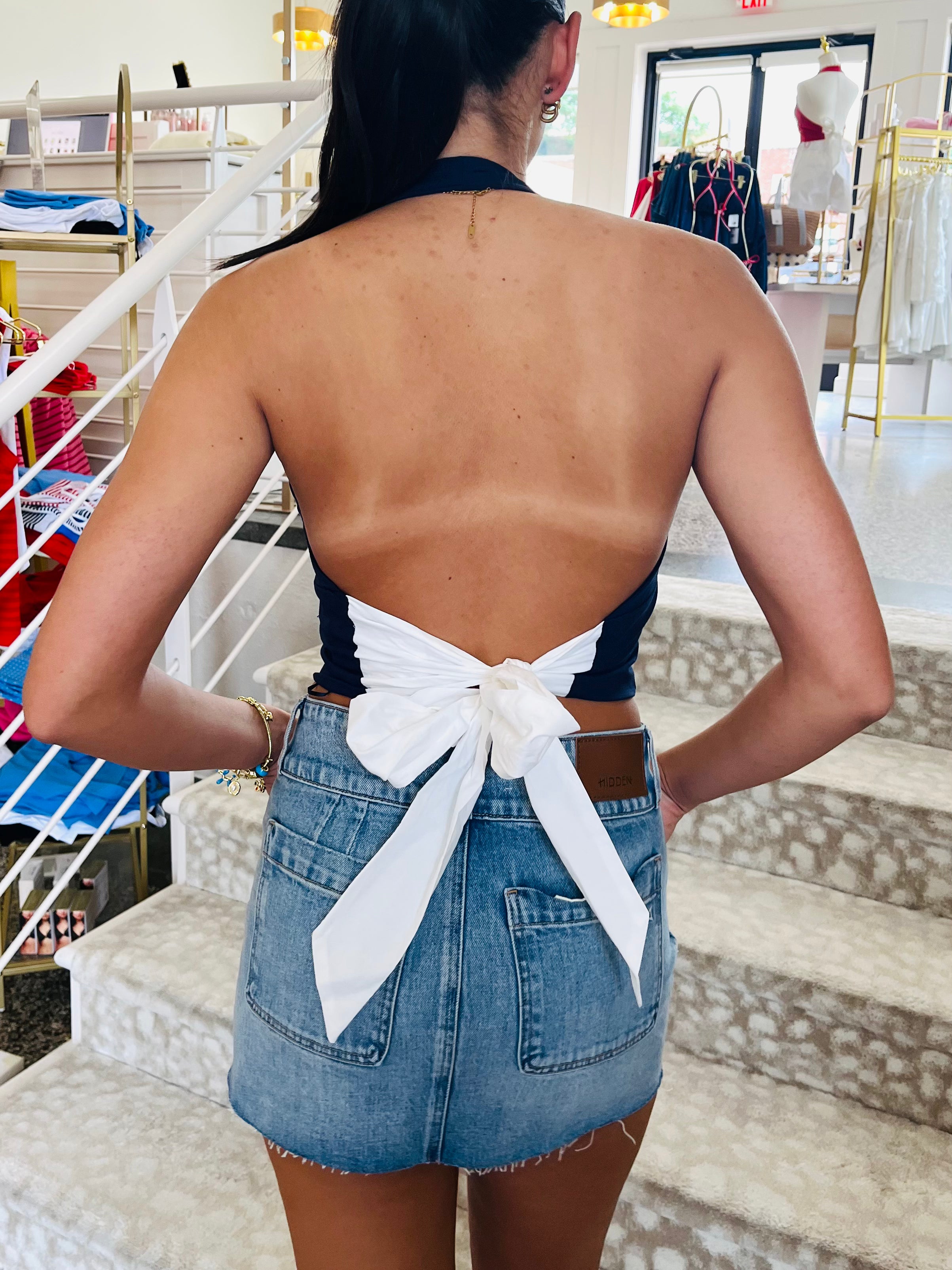 Person wearing a denim skirt with a white ribbon in an indoor setting