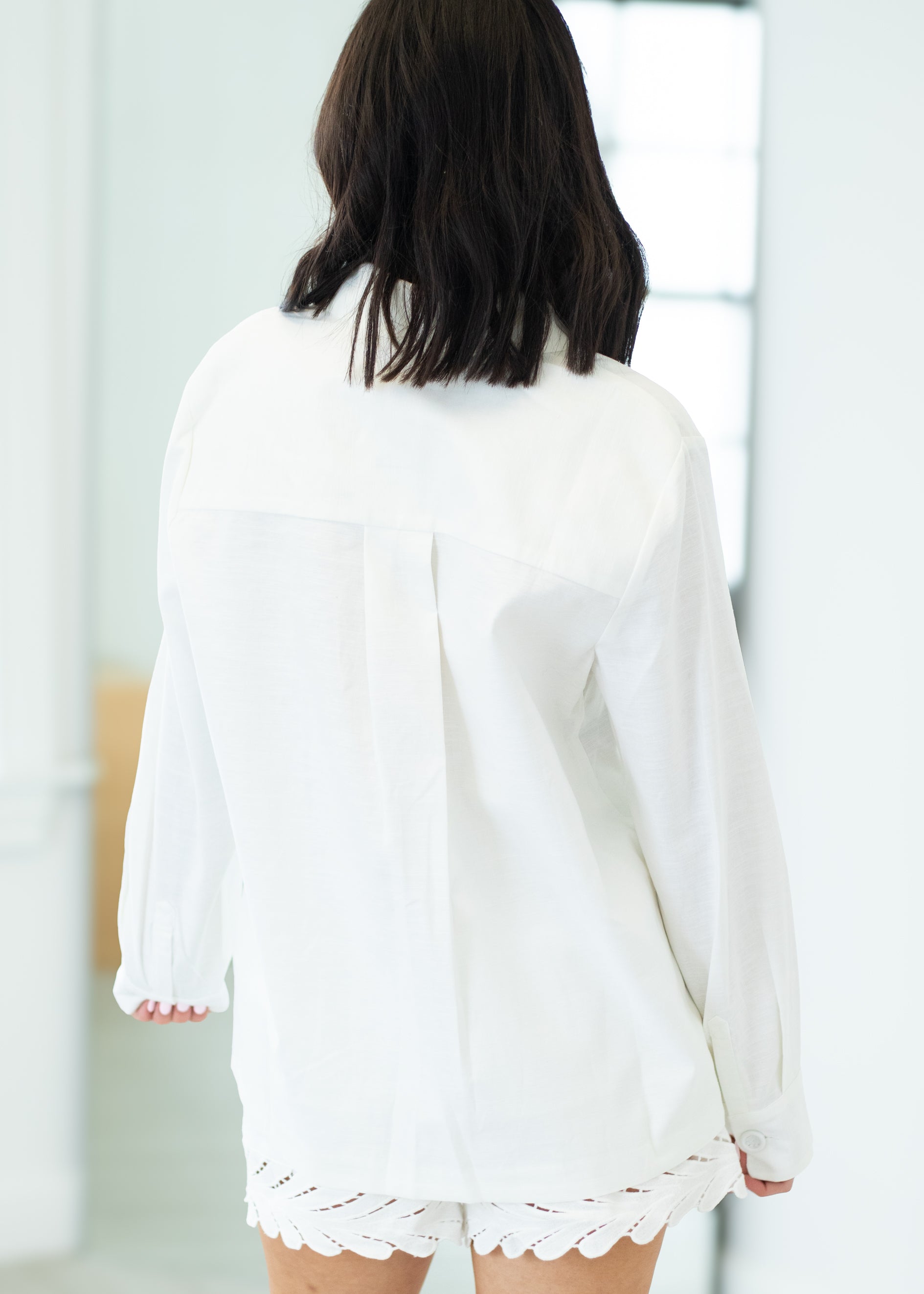 Person wearing a white outfit with lace details in a minimal indoor setting
