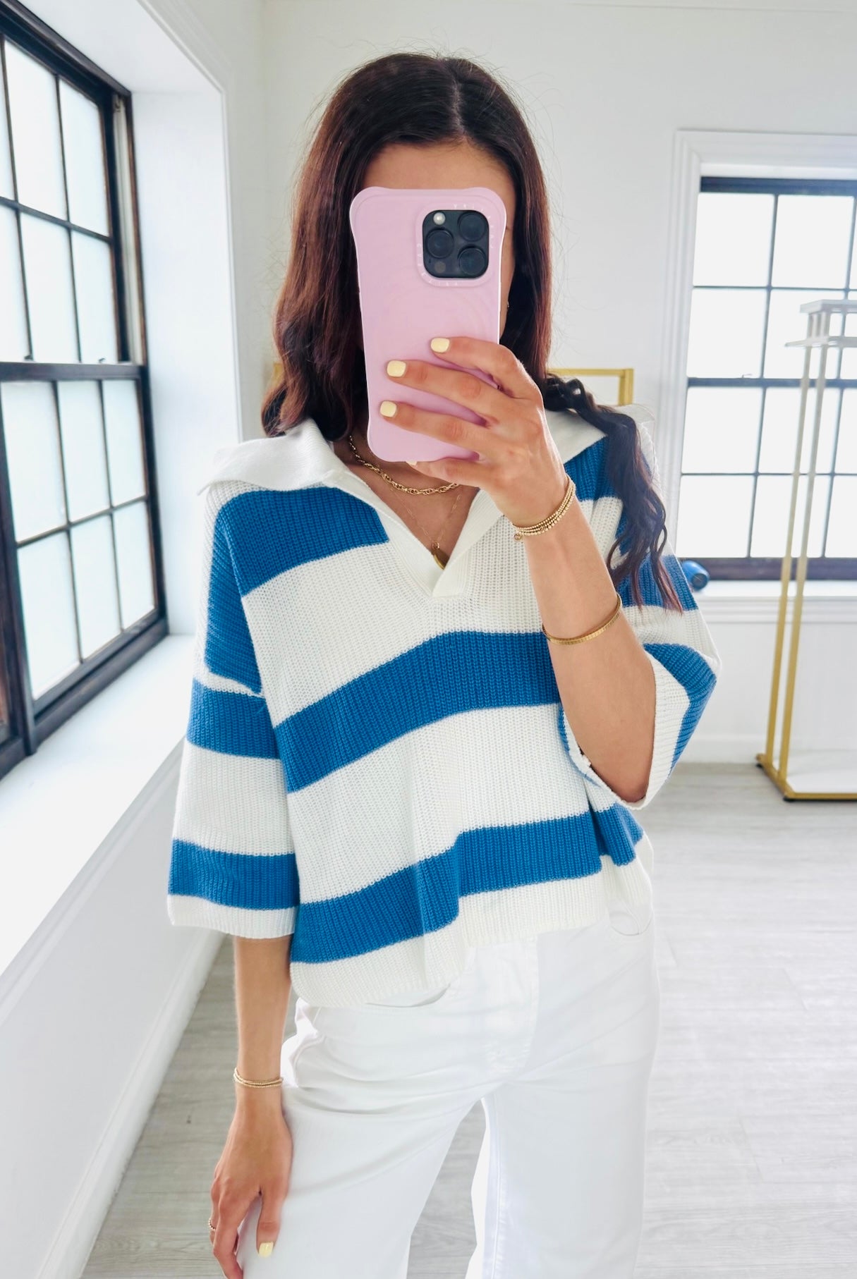 Person wearing a blue and white striped sweater in a bright room.