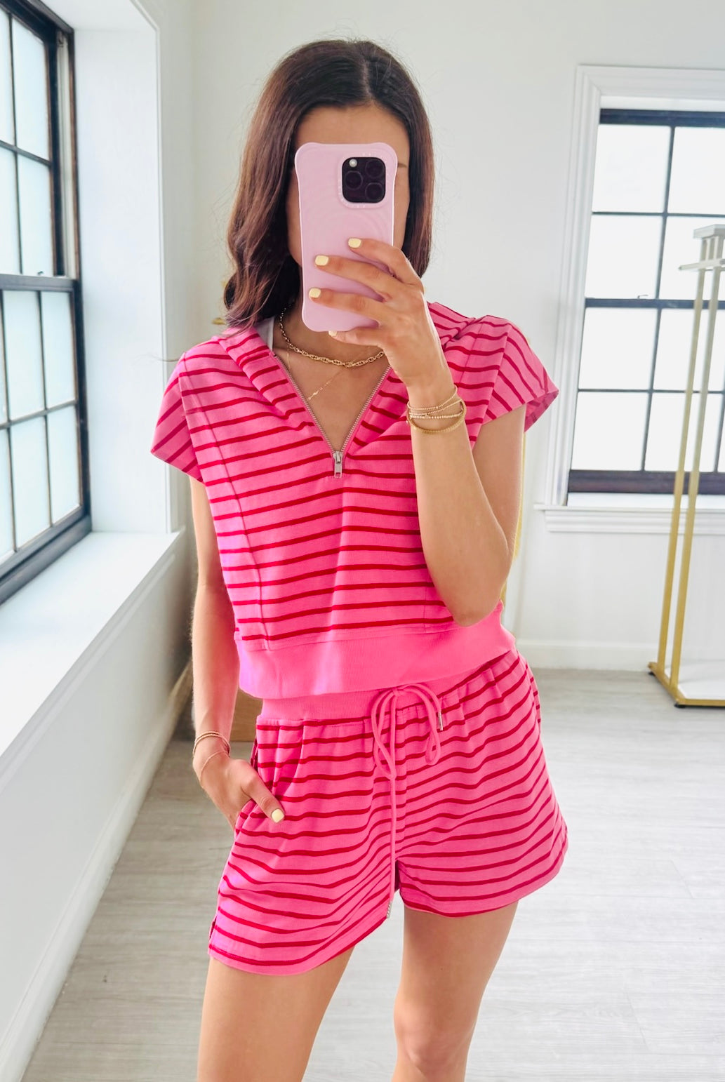 Person wearing a pink and red striped romper taking a mirror selfie.