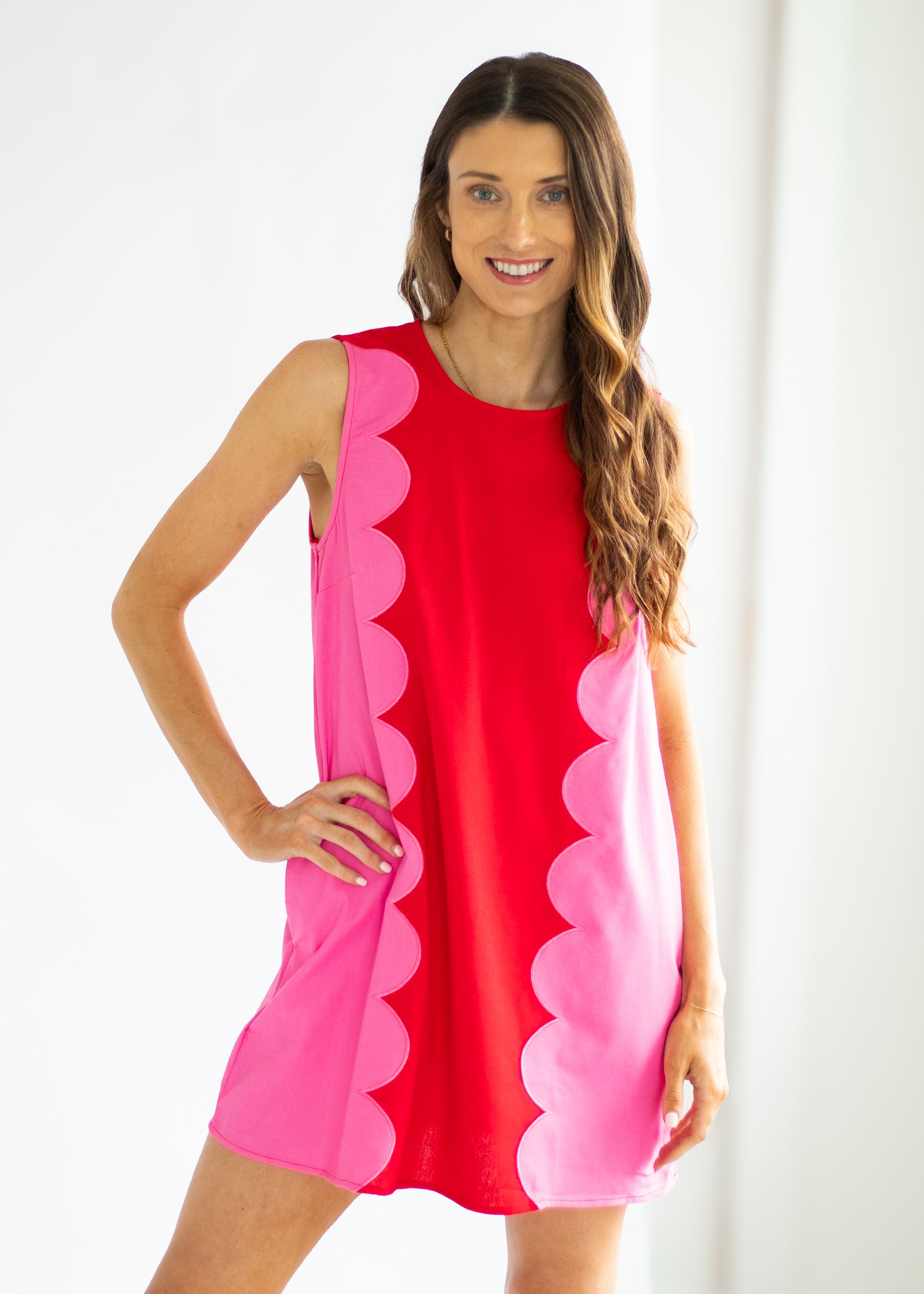 Woman wearing a red and pink dress with scalloped edges on a white background