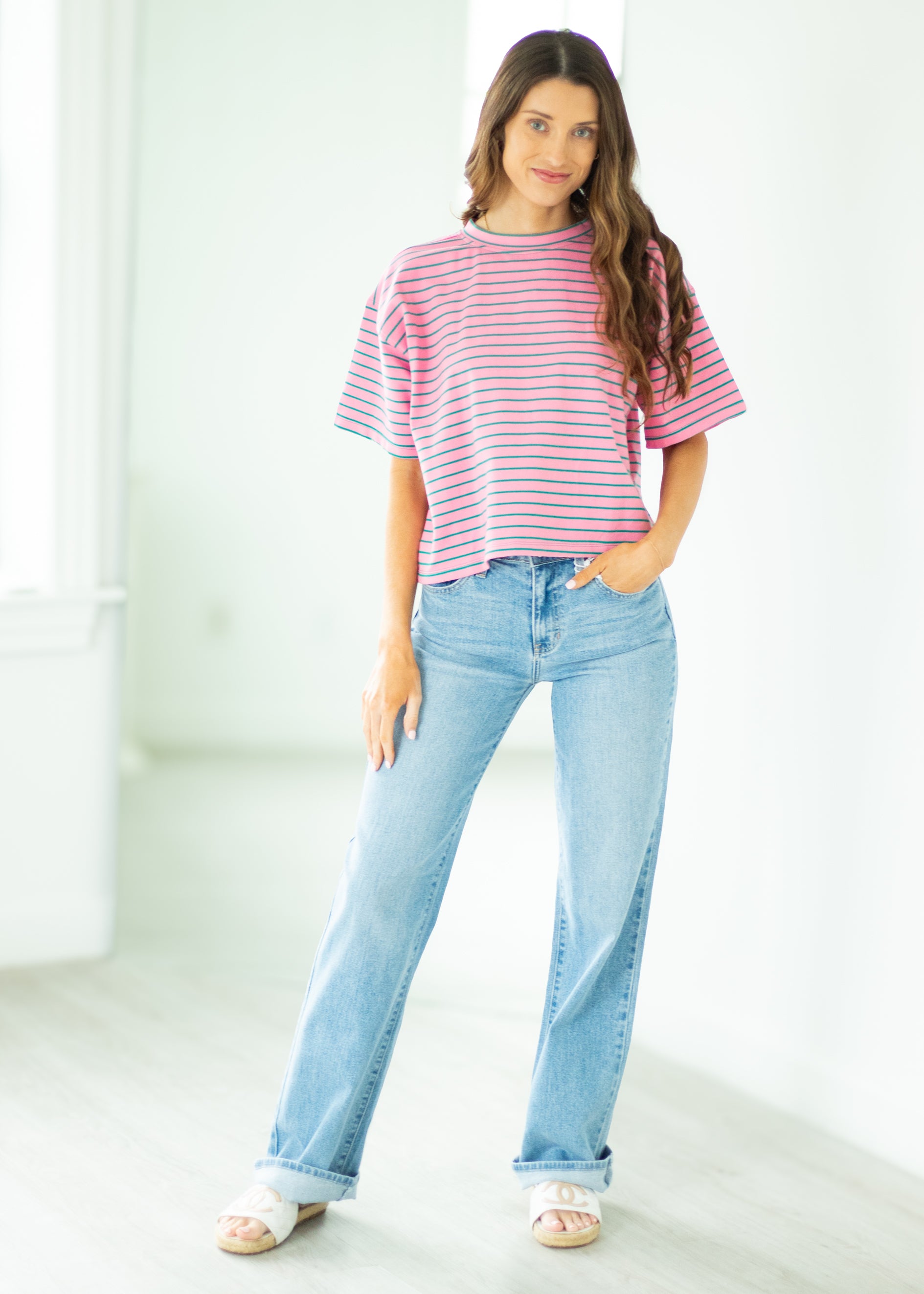 Woman wearing a striped shirt and jeans in a bright room