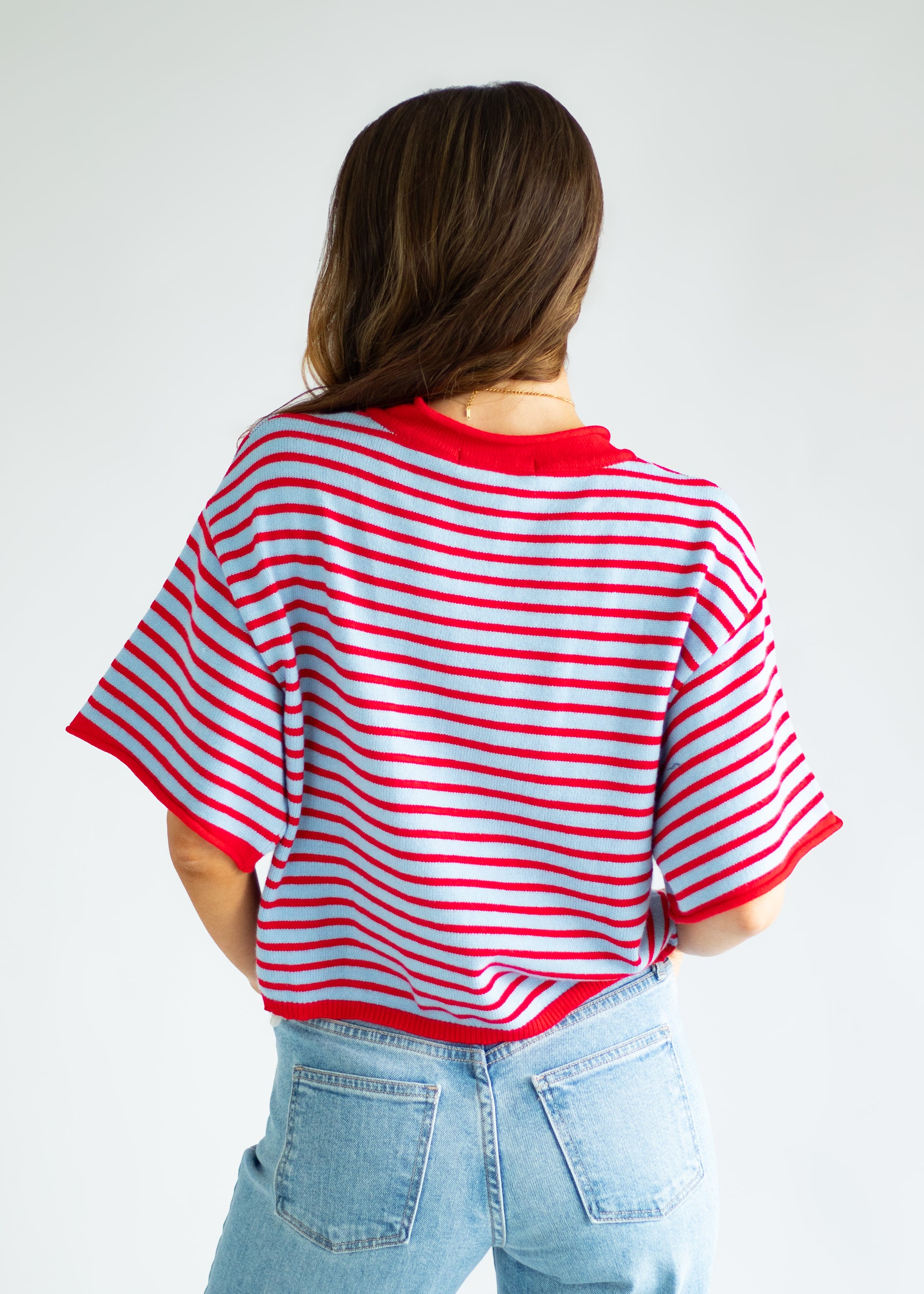 Person wearing a red and white striped shirt with a plain background