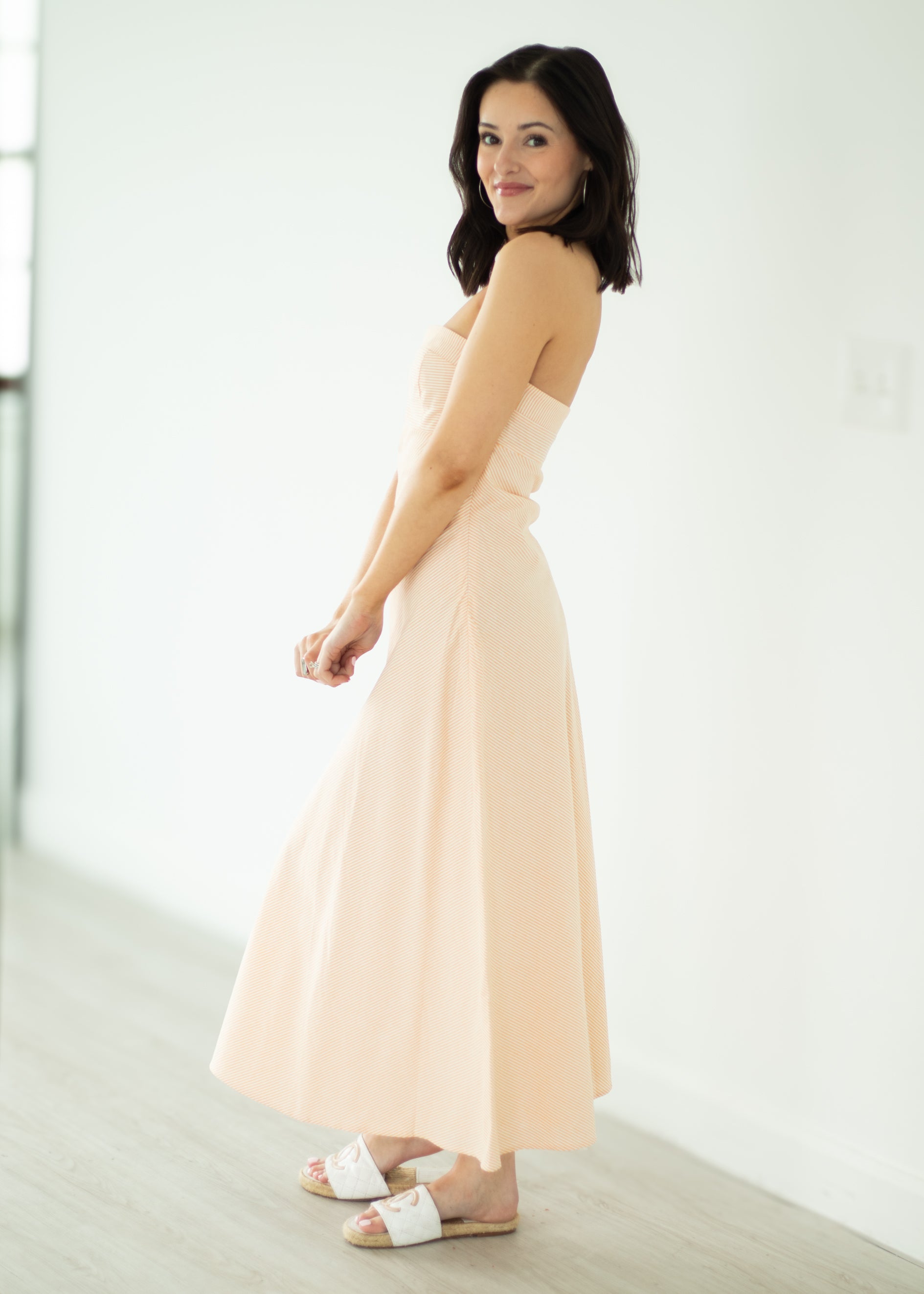 Woman wearing a strapless beige dress in a minimalistic setting