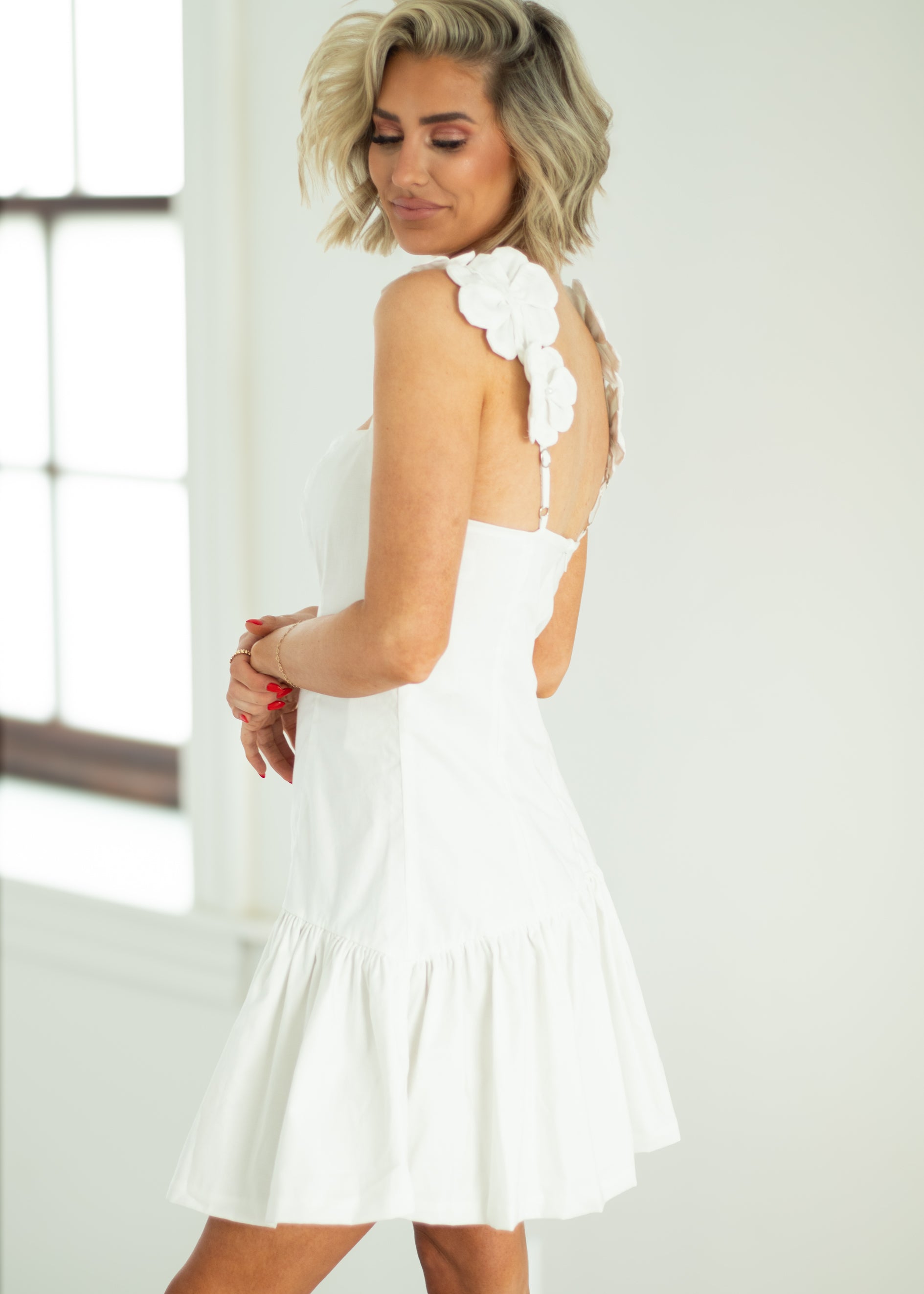 Woman wearing a white dress with floral details in a bright room