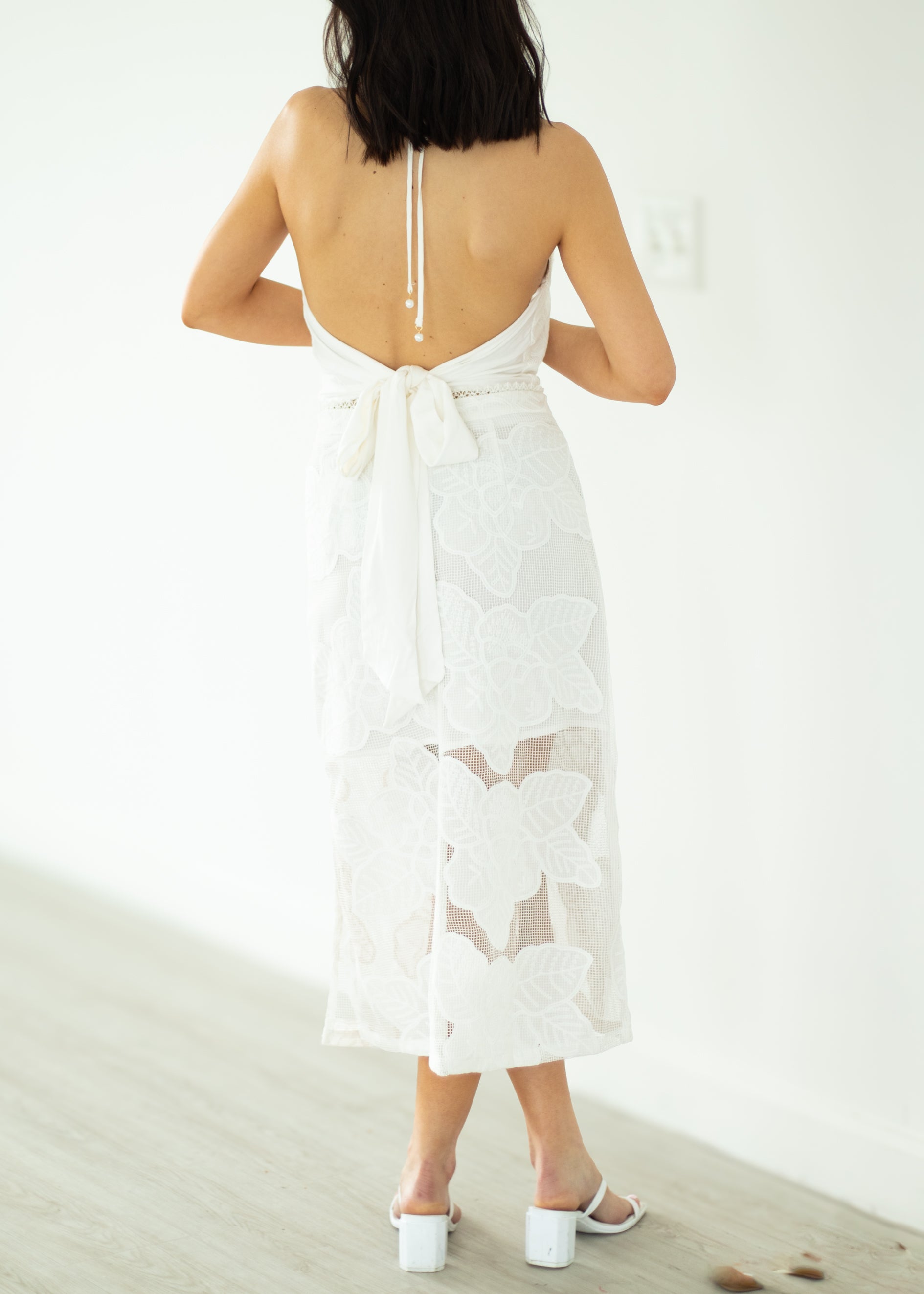Woman wearing a white dress with cut-out design on a white background