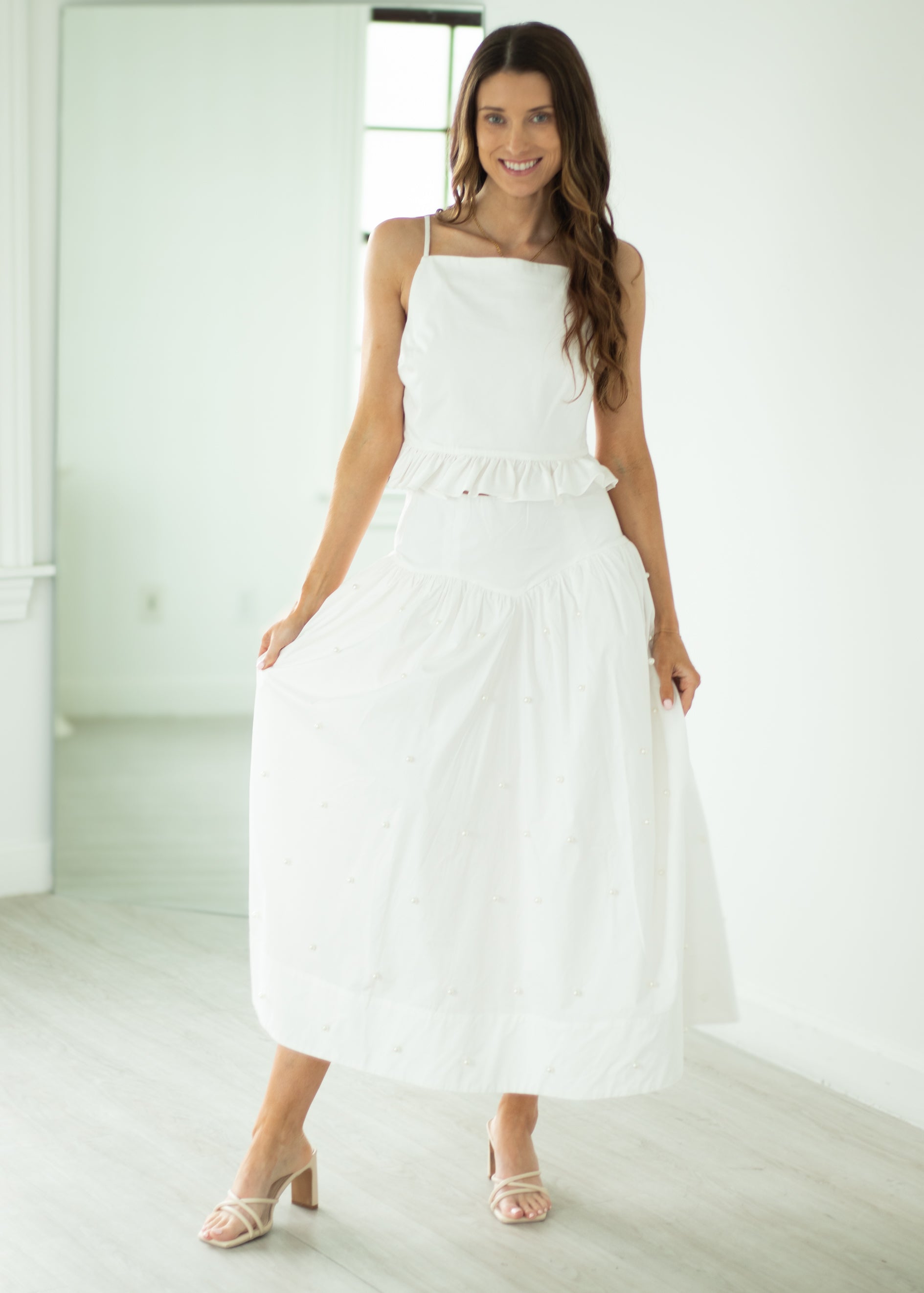 Woman wearing a white dress standing in a bright room.