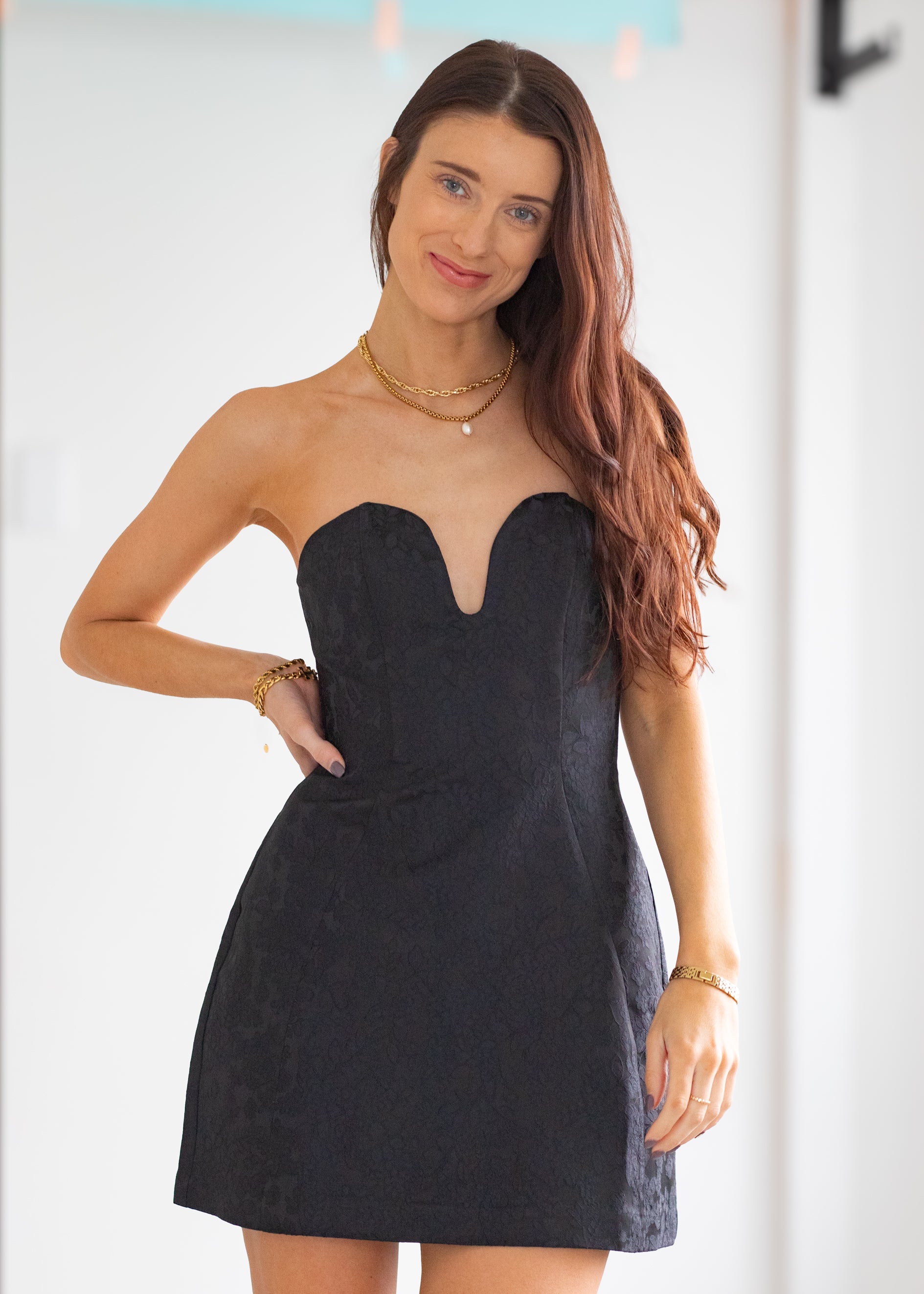 Woman wearing a strapless black dress with a plain background