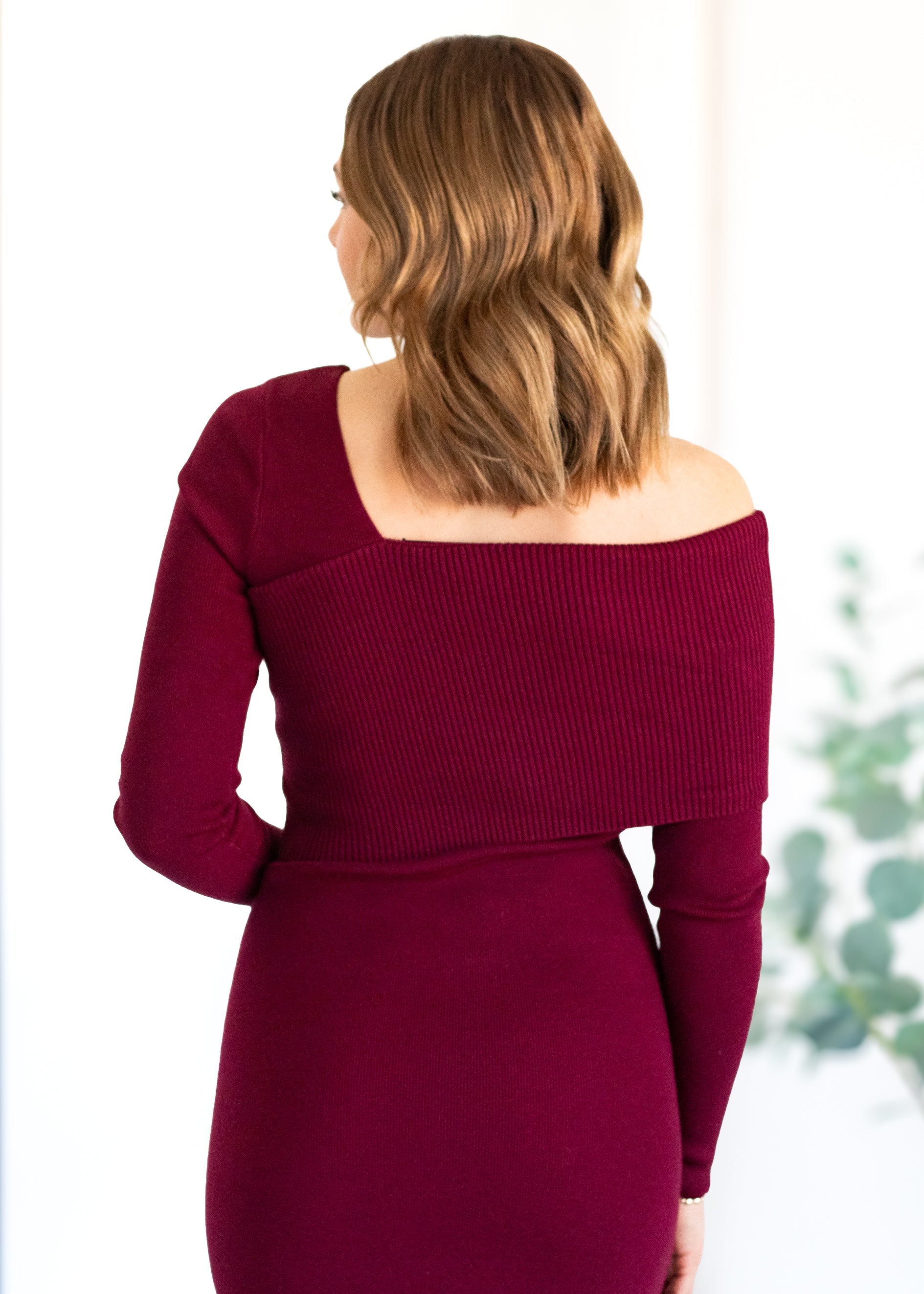 Woman wearing a burgundy off-shoulder dress with a blurred background