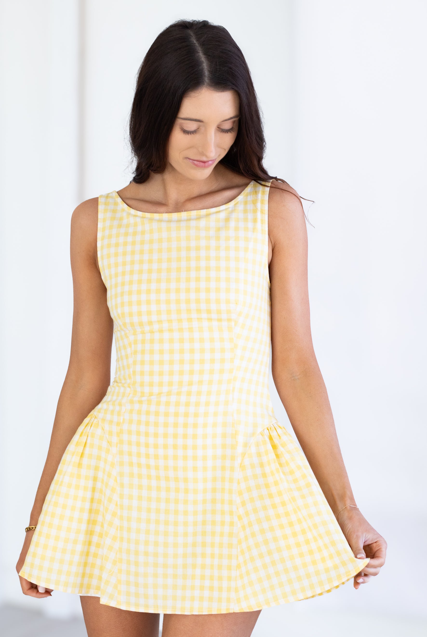 Woman wearing a yellow checkered dress against a white background