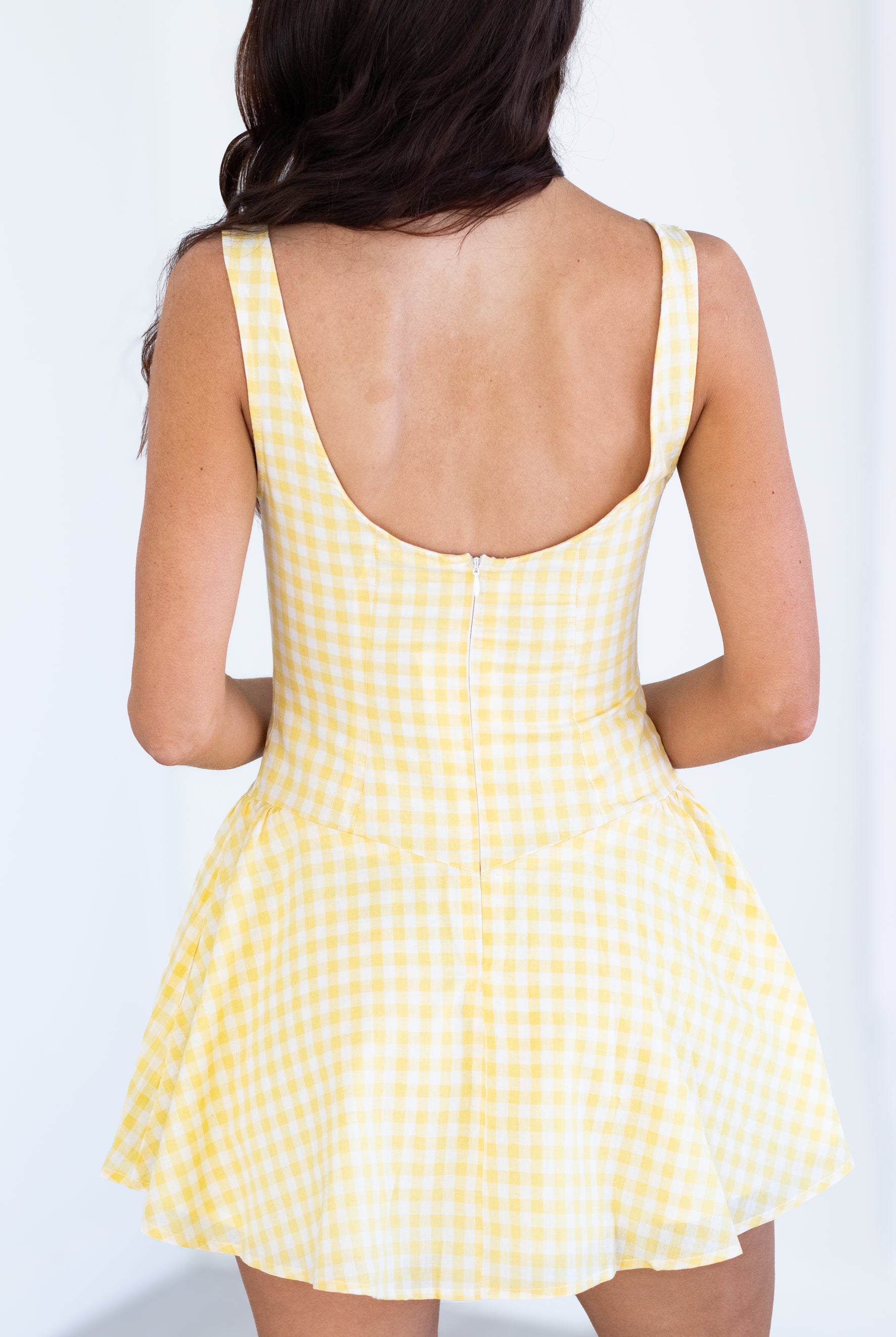 Yellow checkered dress worn by a person on a white background