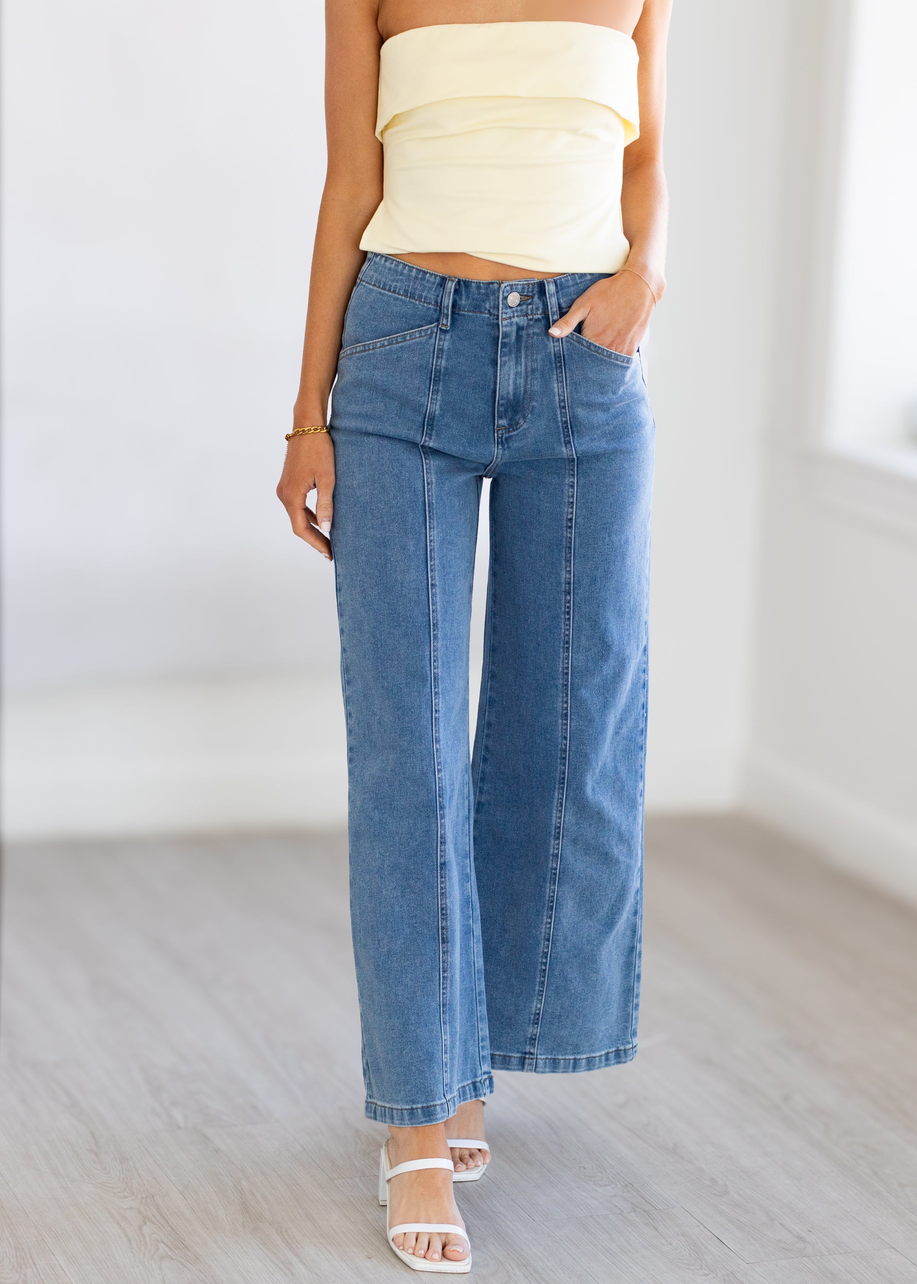 Person wearing a yellow top and blue jeans on a plain background