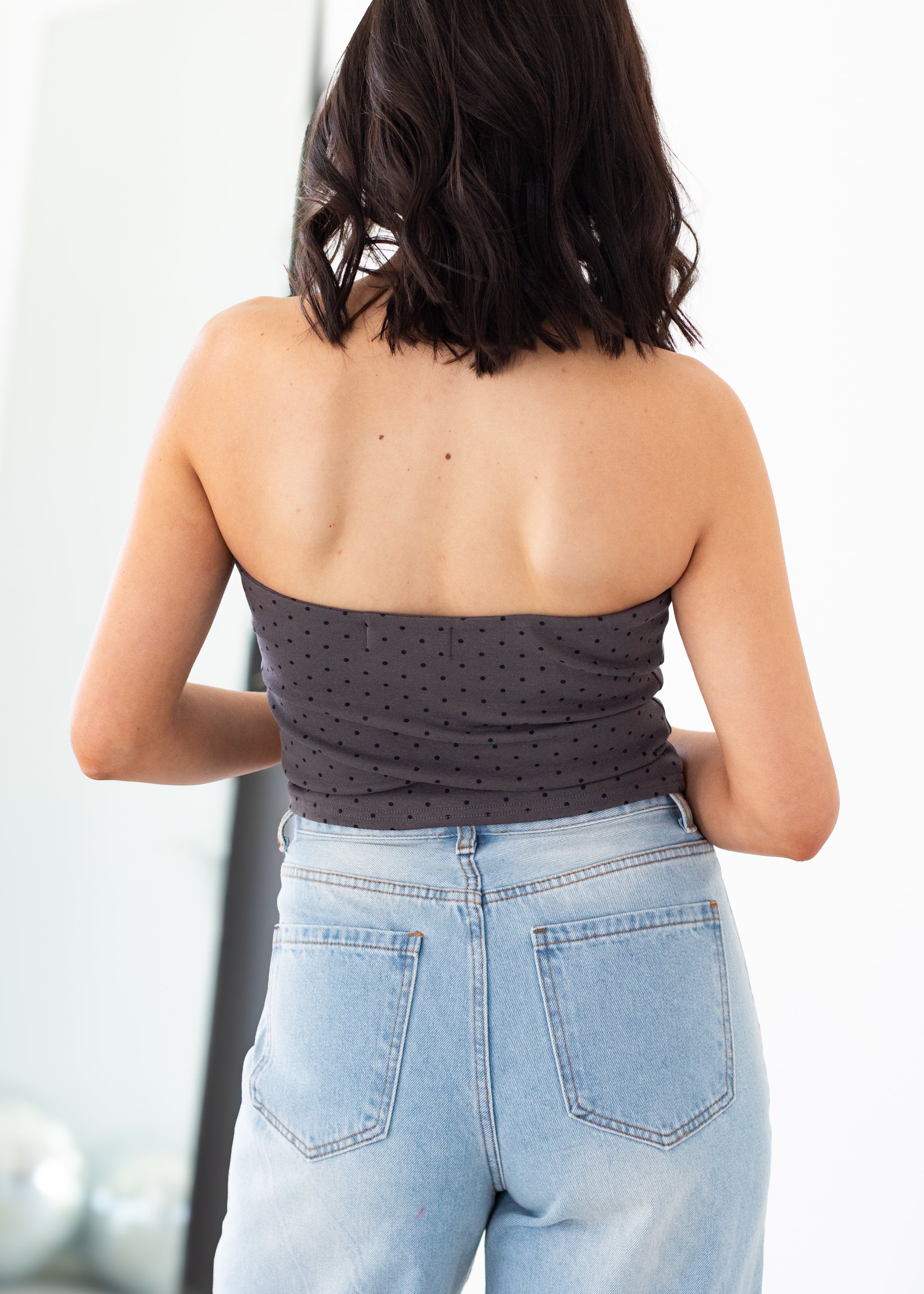 Person wearing a strapless top and light blue jeans with a blurred background