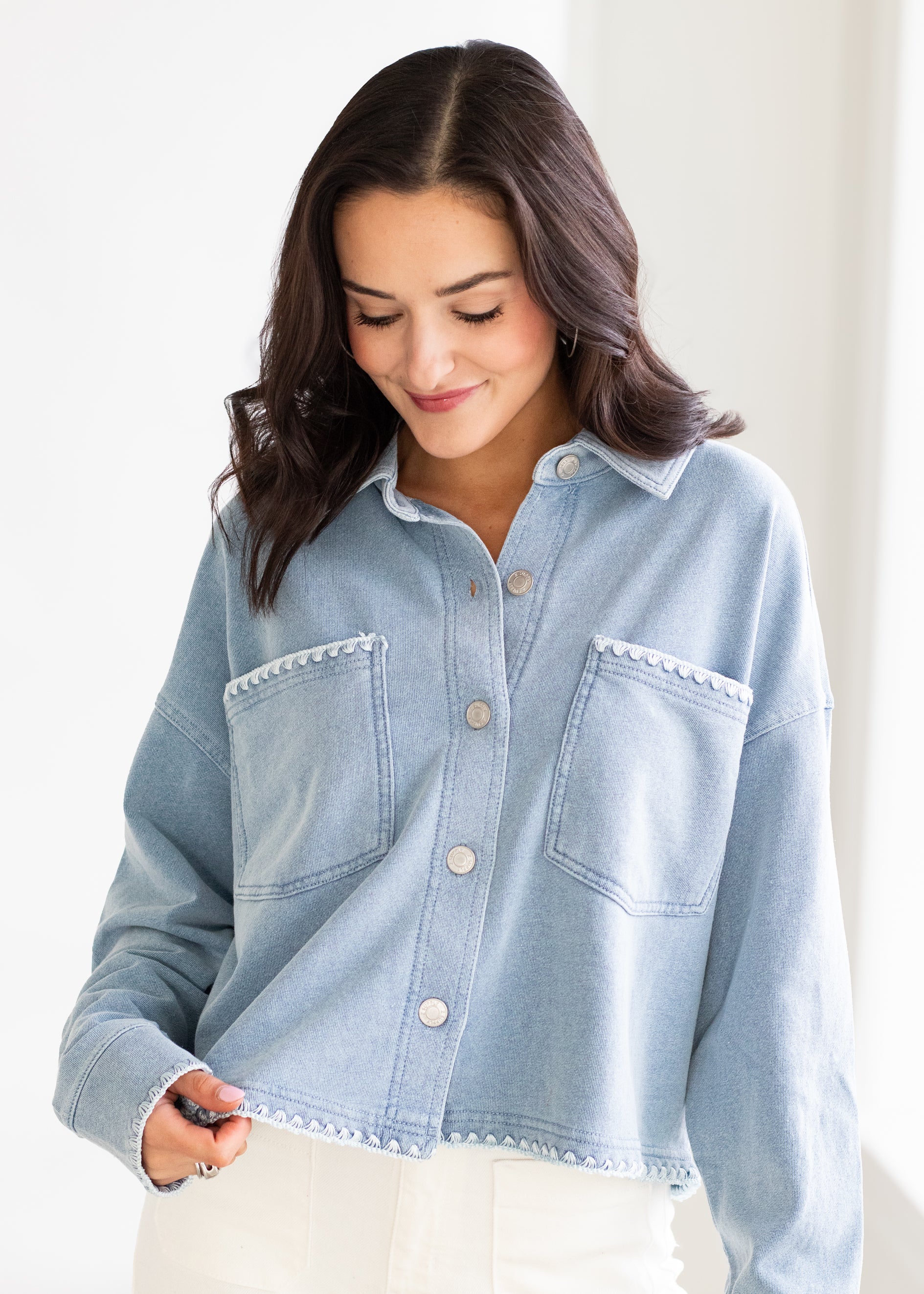 Woman wearing a light blue denim shirt against a white background