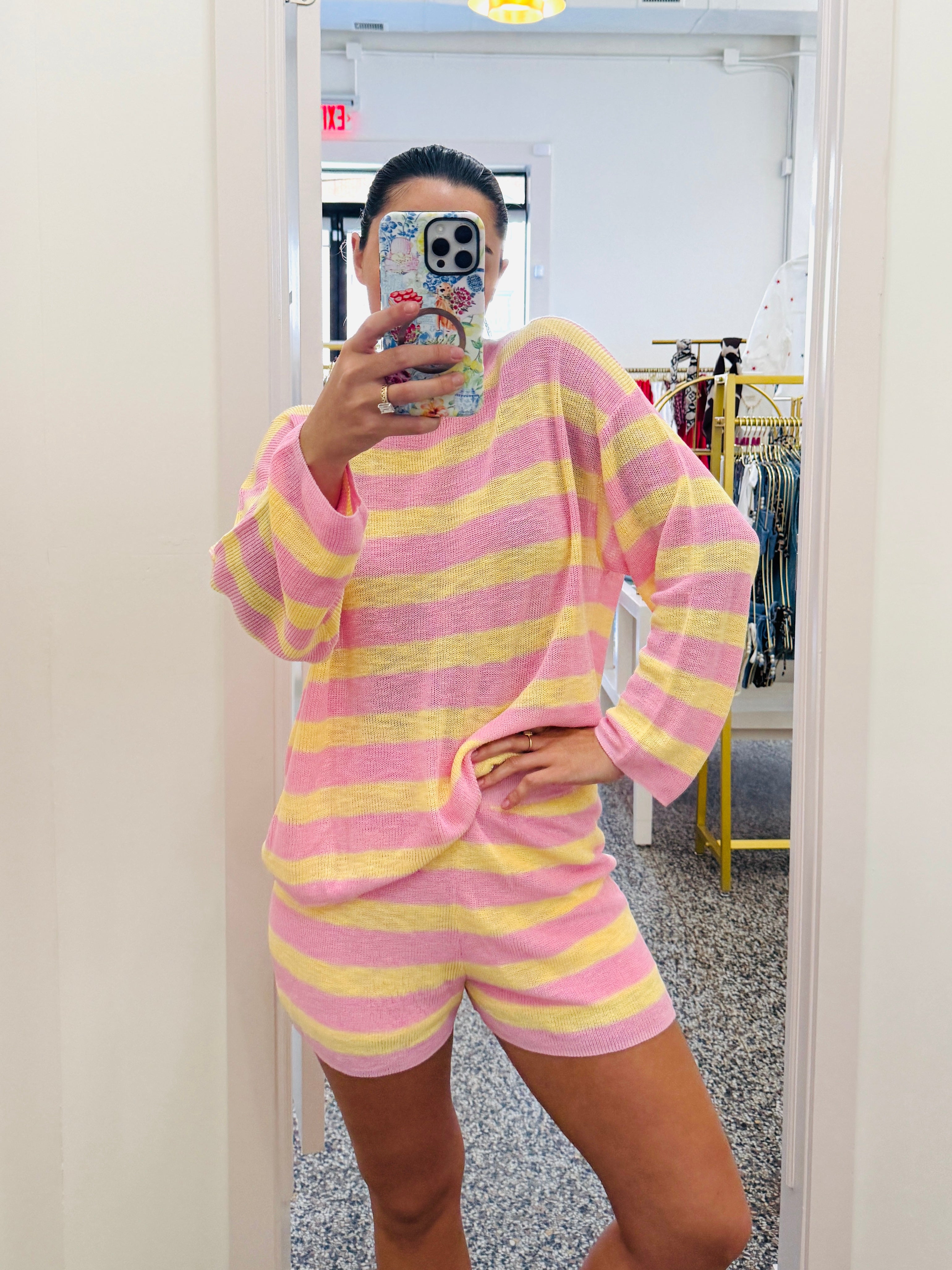 Person wearing a pink and yellow striped outfit taking a mirror selfie.